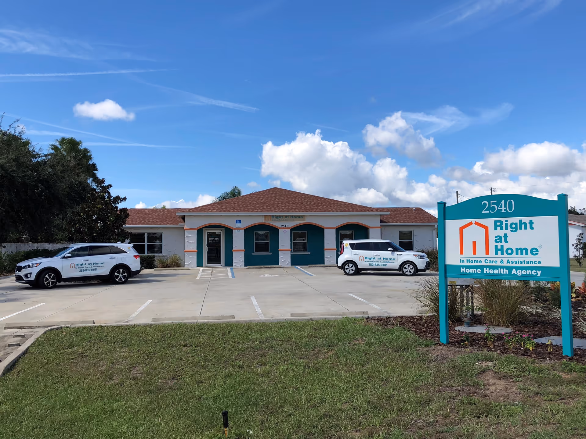 Front exterior of a Right at Home facility with teal trim and parked company cars.