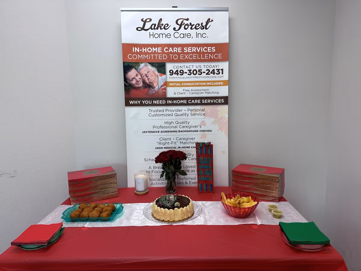 Indoor display table with a Lake Forest Home Care banner and assorted snacks.