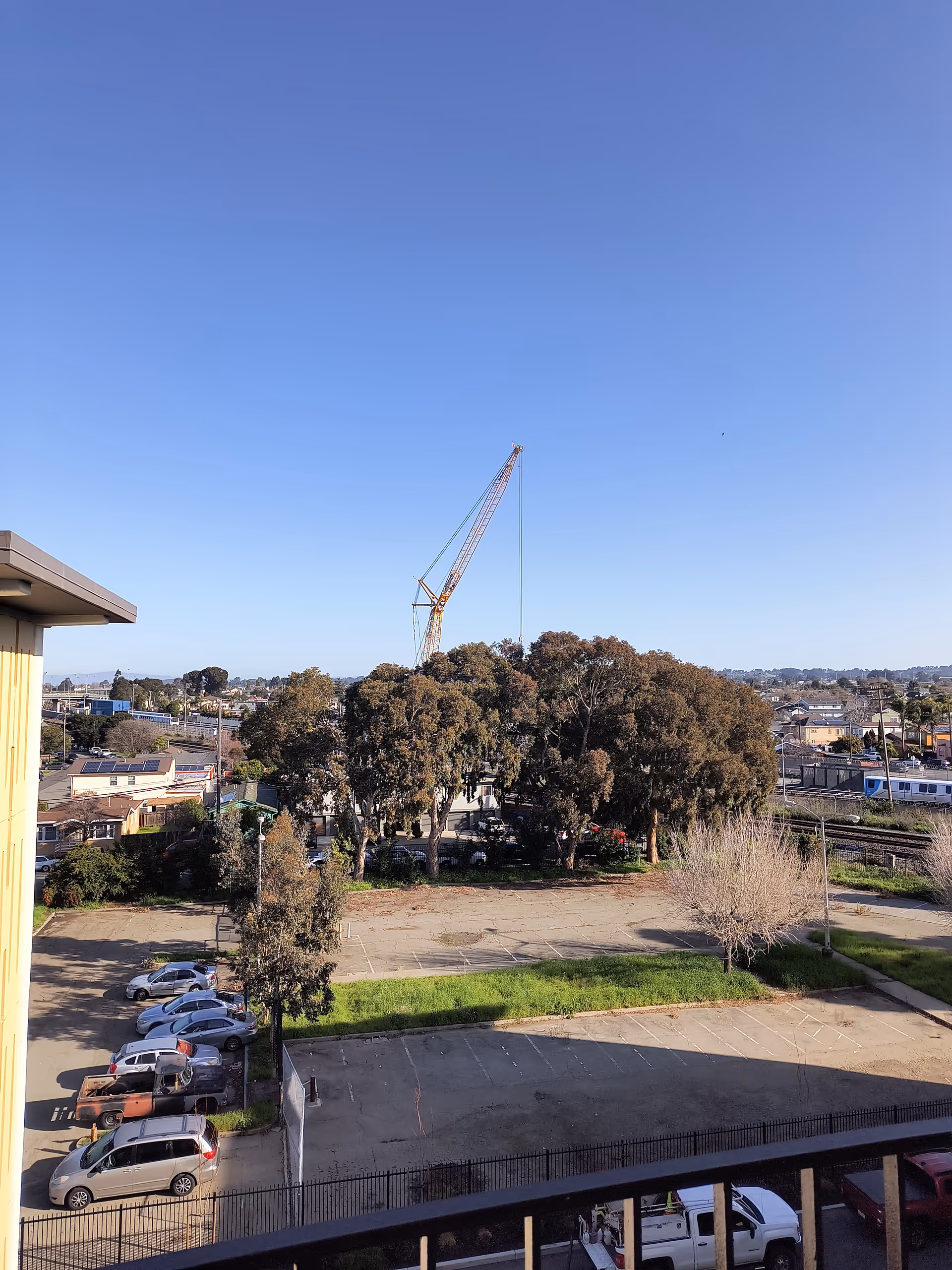 Balcony view of parking lot, trees, and a construction crane beyond the facility.