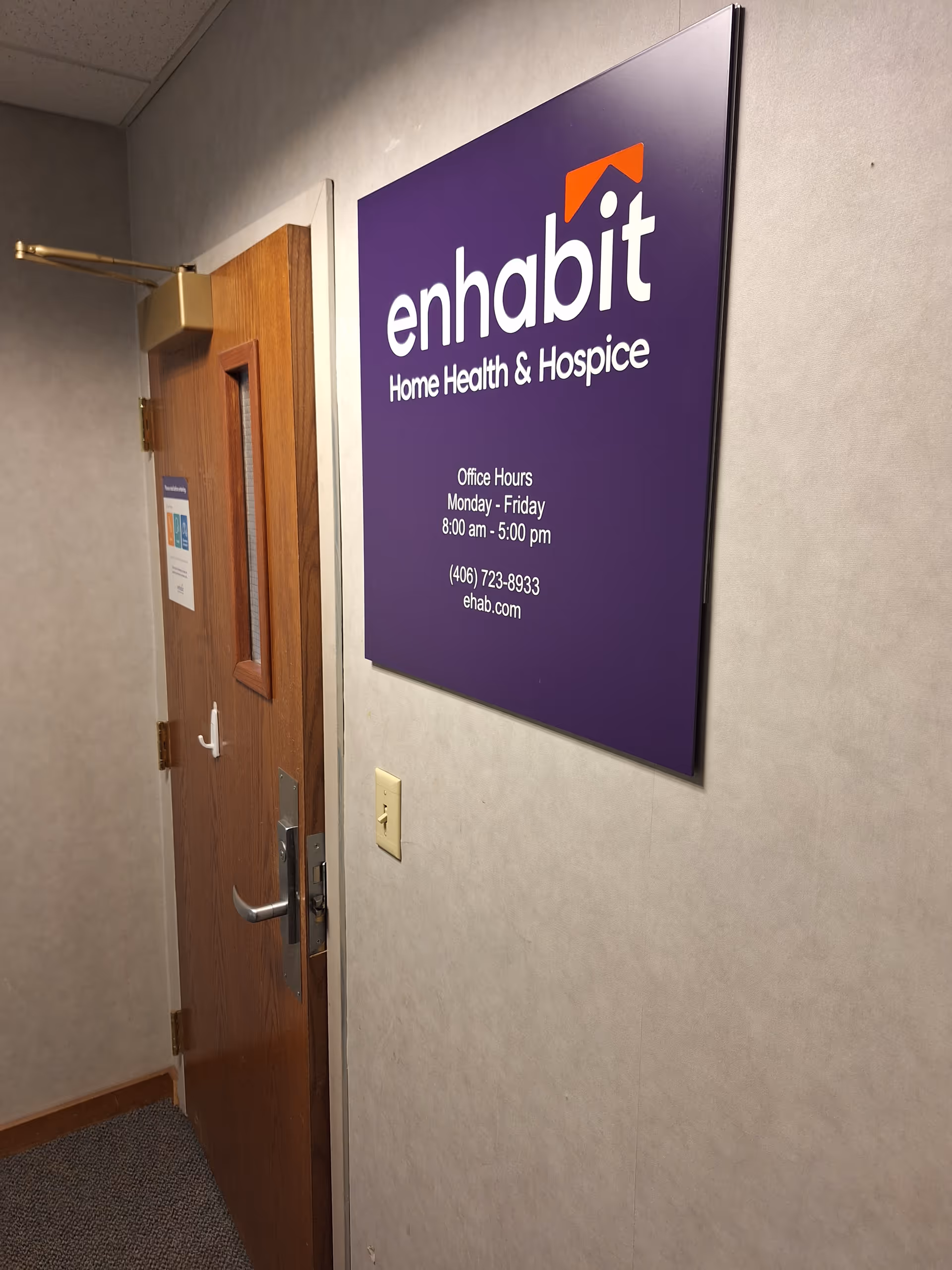 A hallway with a large purple Enhabit Home Health & Hospice sign on the wall.