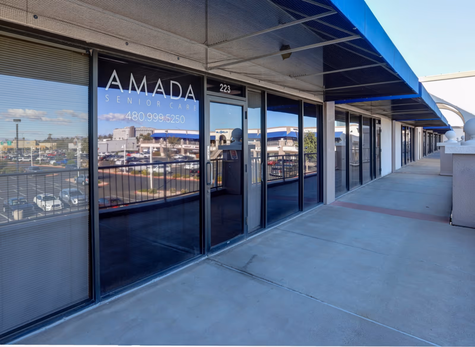 Exterior storefront of Amada Senior Care with glass doors along a covered walkway.