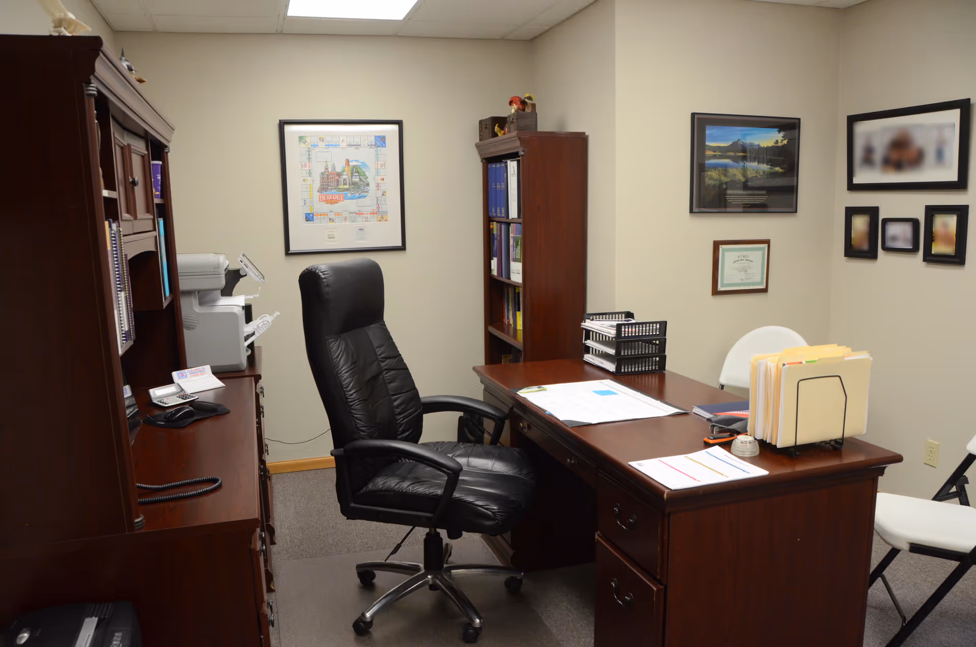 A well-organized office with a wooden desk, leather chair, and bookshelves.