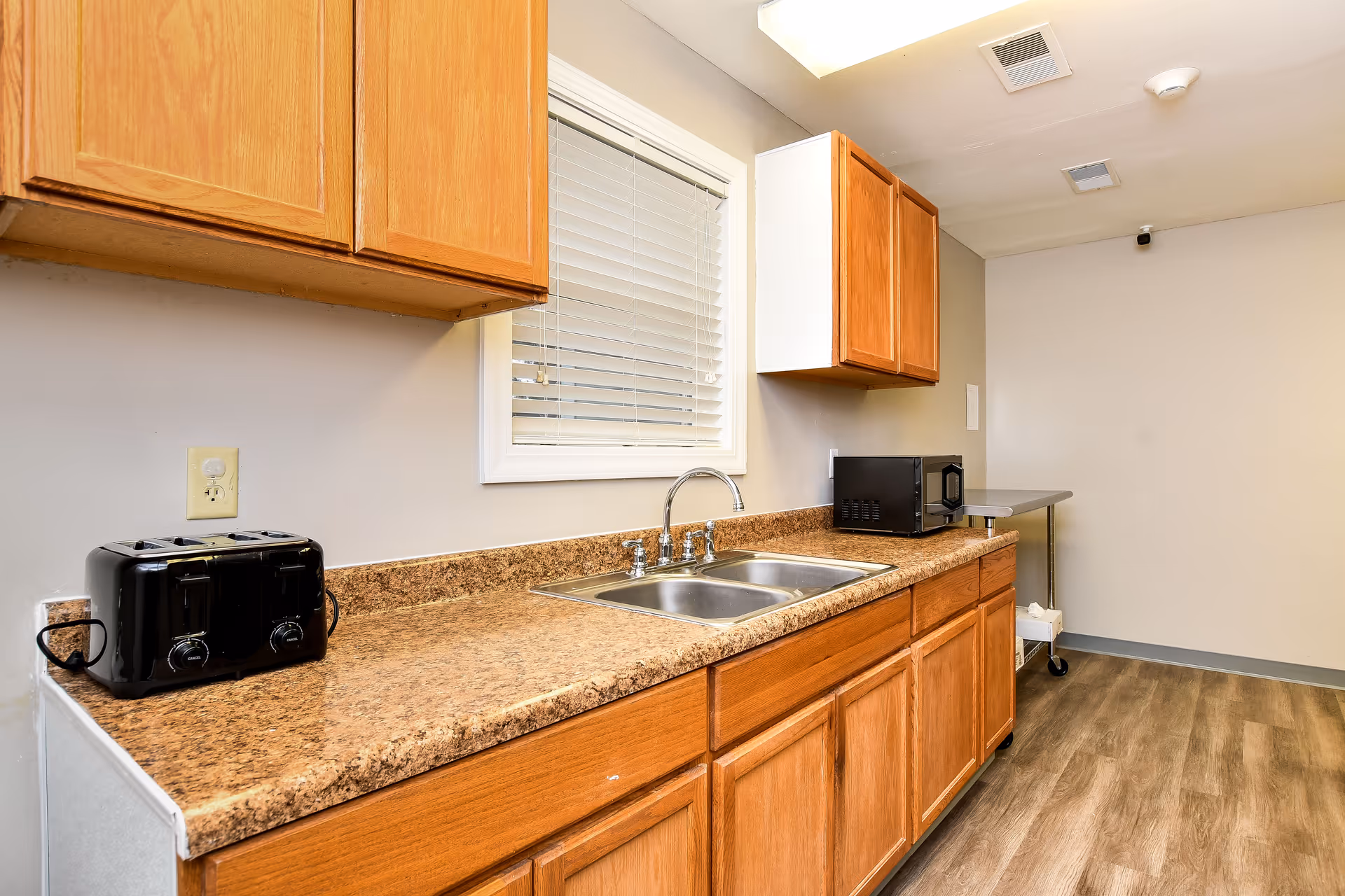 Wooden kitchen cabinets over granite counter with sink, toaster, and microwave.