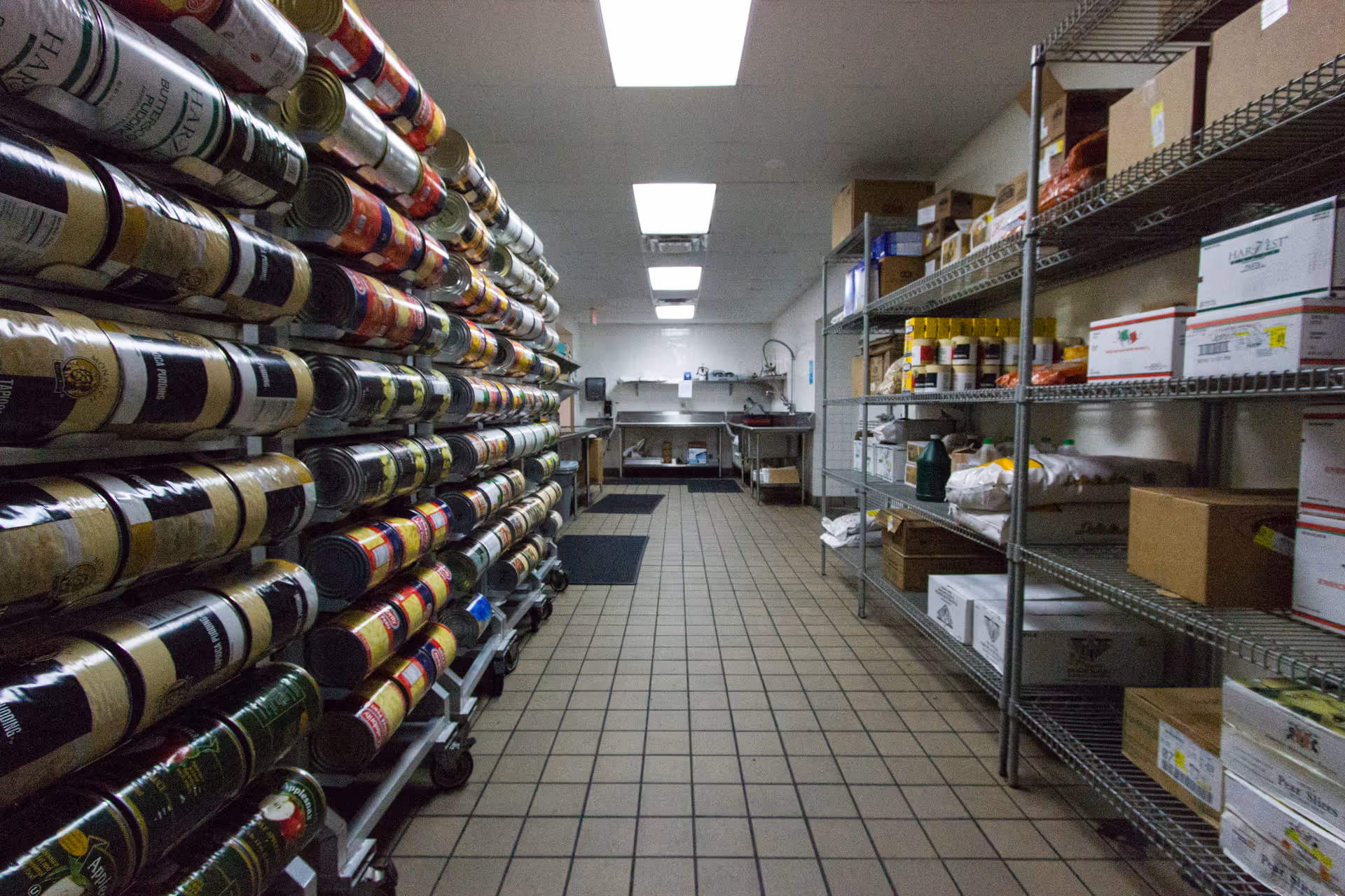 Narrow storage room with stacked rolls on the left and metal shelving on the right.