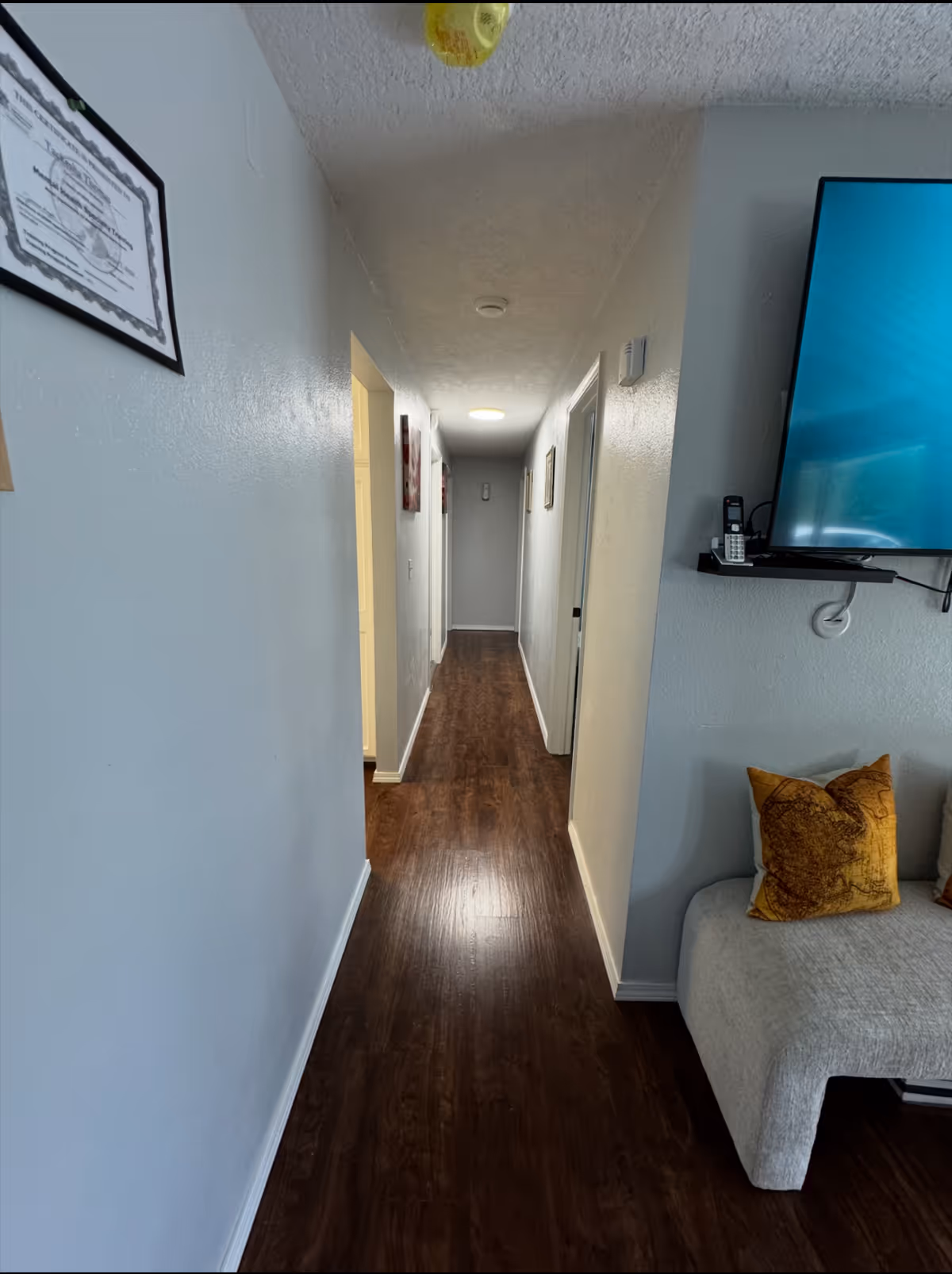 Narrow hallway in Empathy Haven AFH LLC with doors, TV, and a couch.