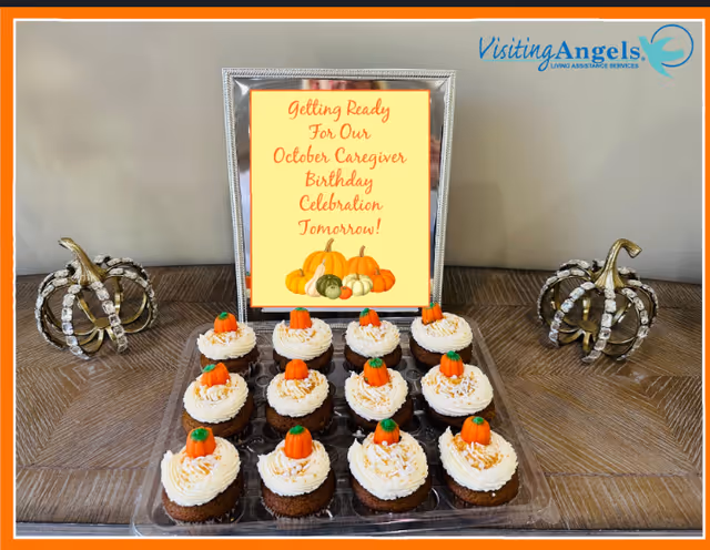 Tray of cupcakes and a framed sign on a table inside a senior care facility.