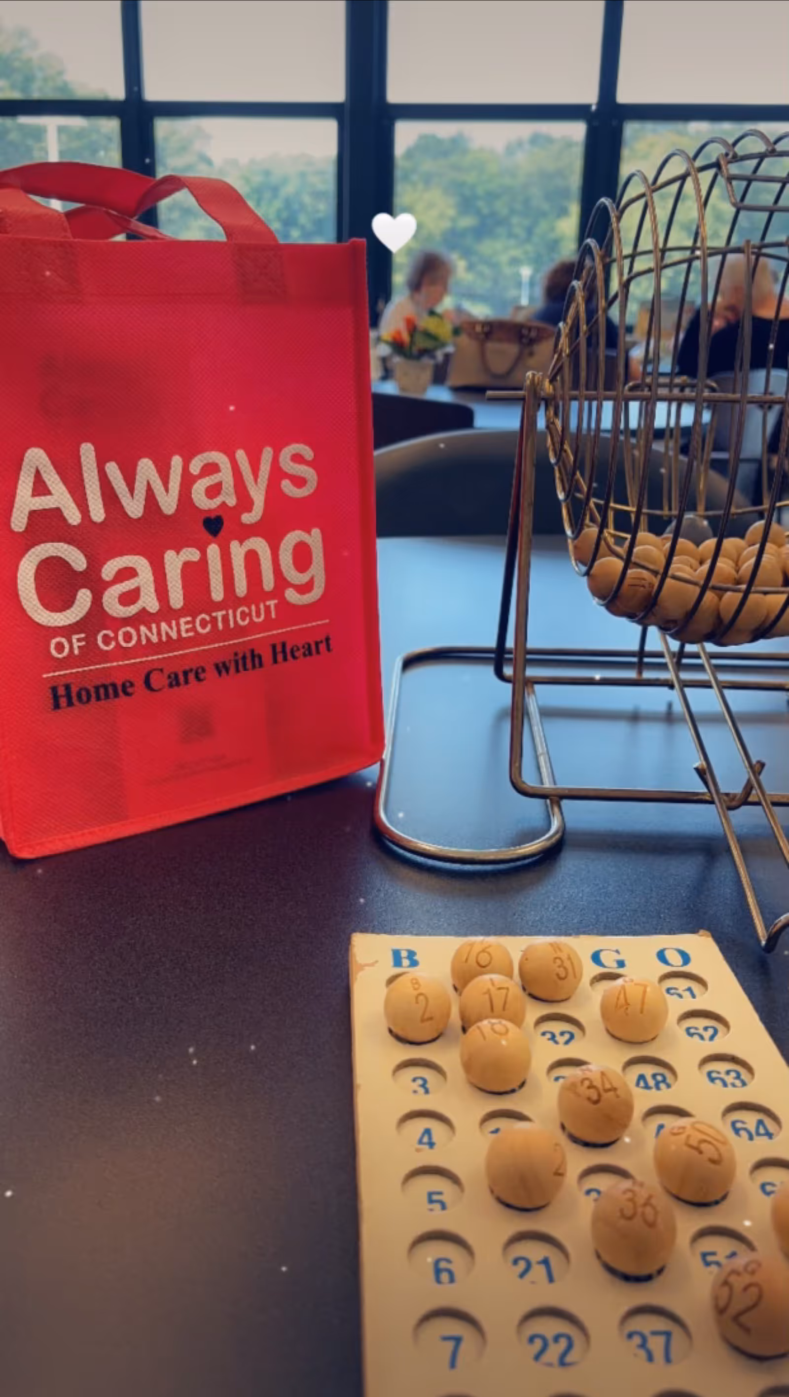 Red Always Caring bag on a table beside a bingo card and wire rack.