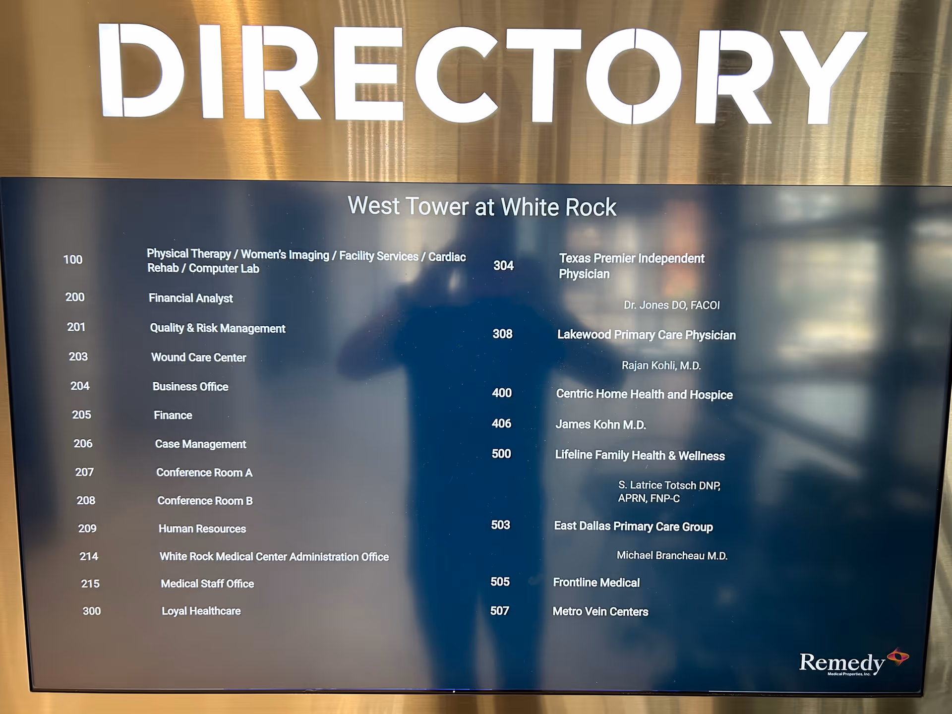 Indoor directory sign listing departments and room numbers inside a medical facility.