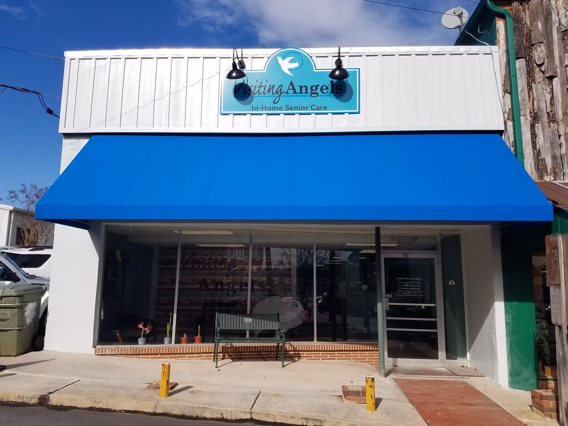 Front view of Visiting Angels storefront with a blue awning and glass entrance.