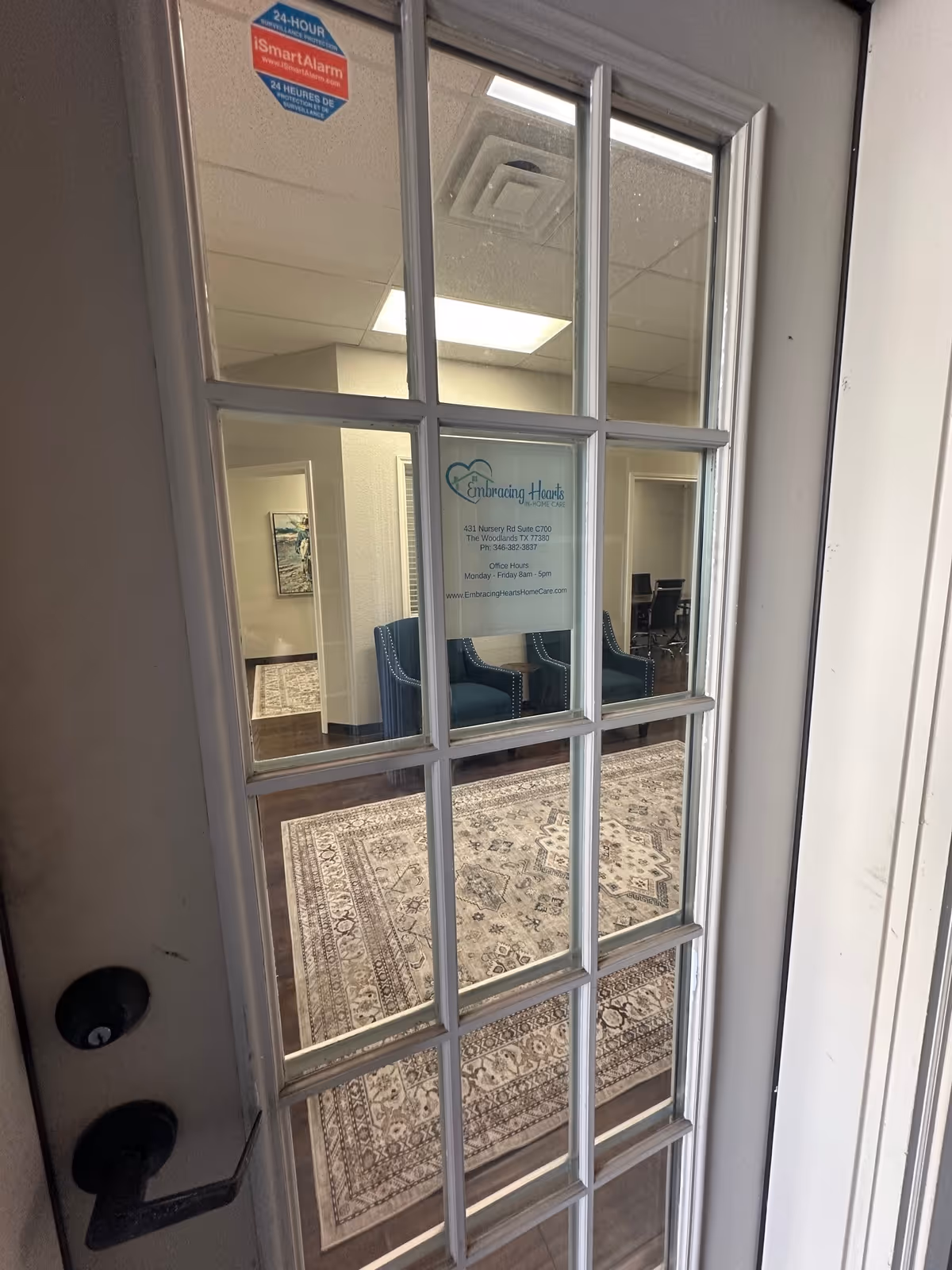 Glass-paned door reveals a waiting area with blue chairs and a patterned rug.