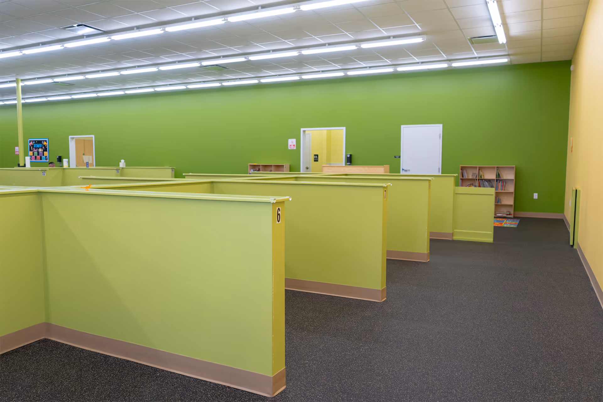 Bright lime-green cubicles fill a large, empty interior therapy space.
