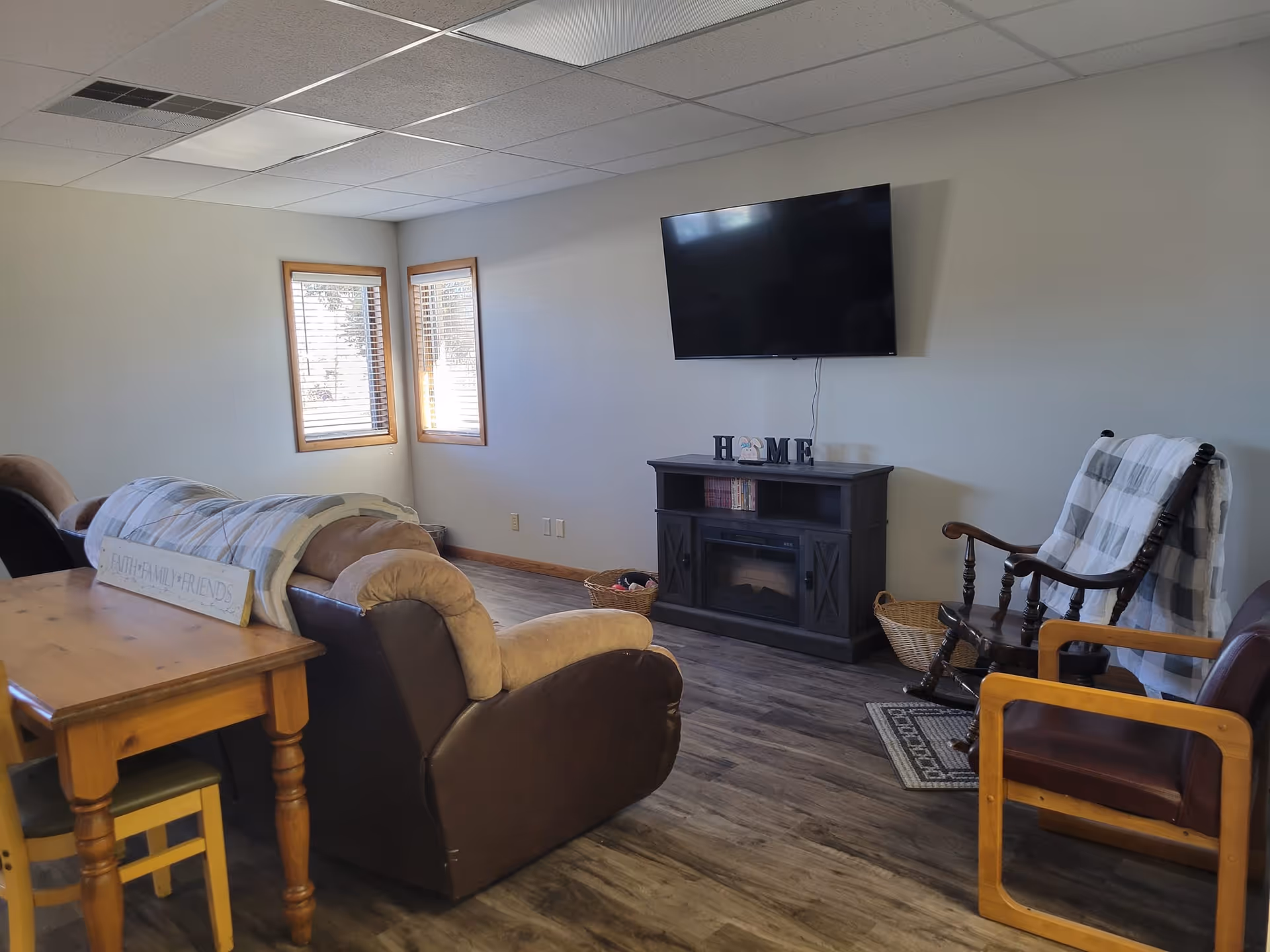 Cozy living room with sofa, chairs, wall-mounted TV, and a fireplace stand.