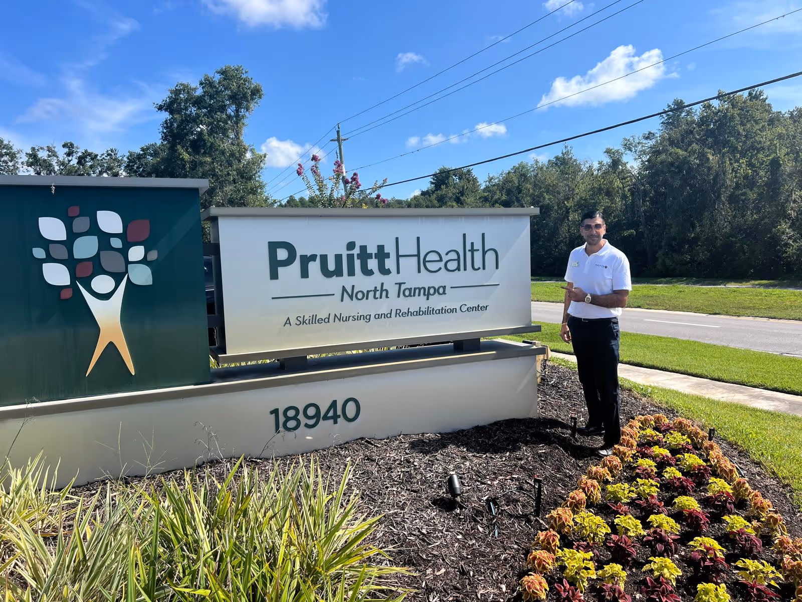 Staff member stands beside PruittHealth North Tampa sign outside a senior care center