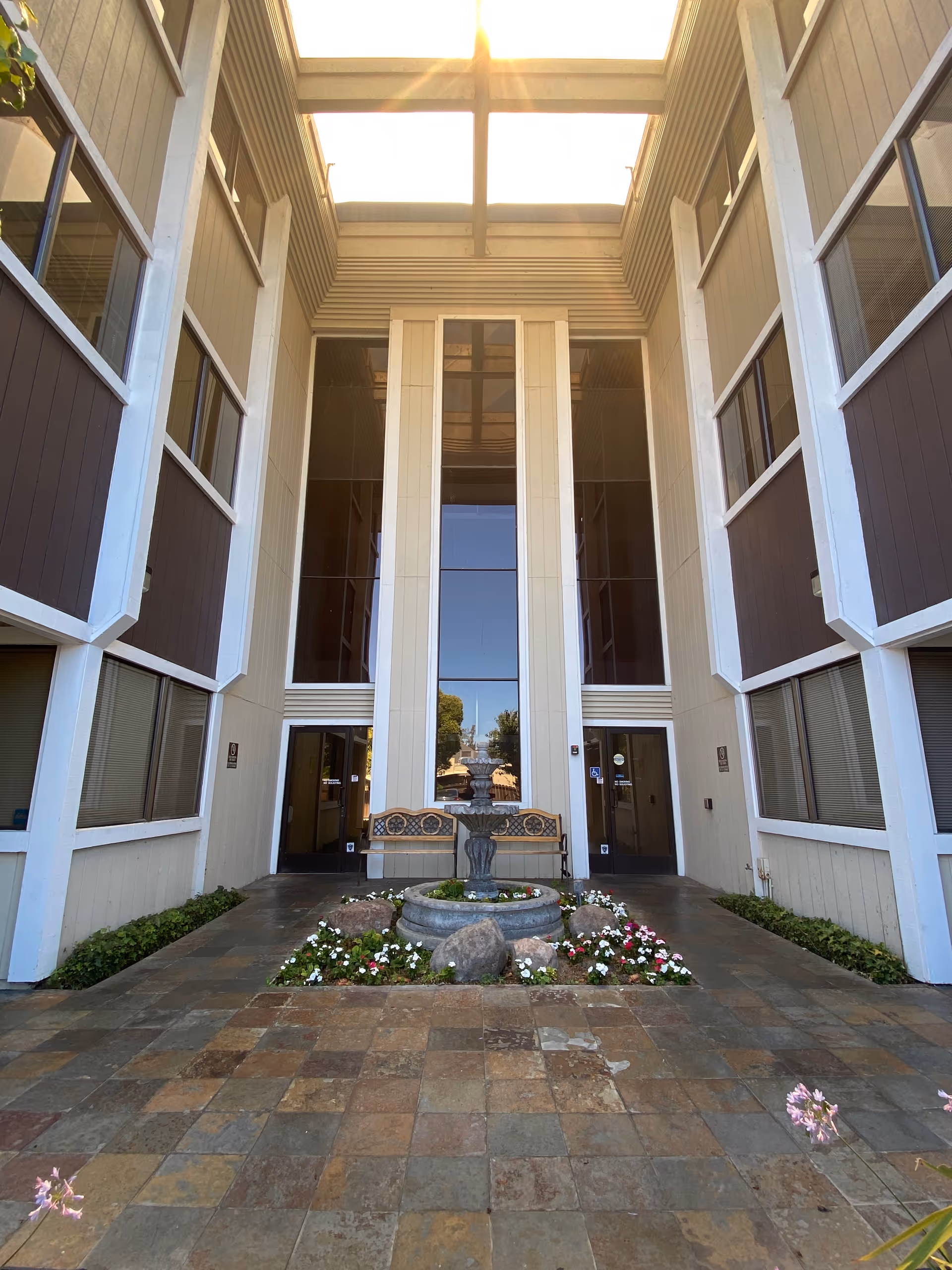 Central courtyard atrium with fountain, benches, and tall glass doors between building wings.