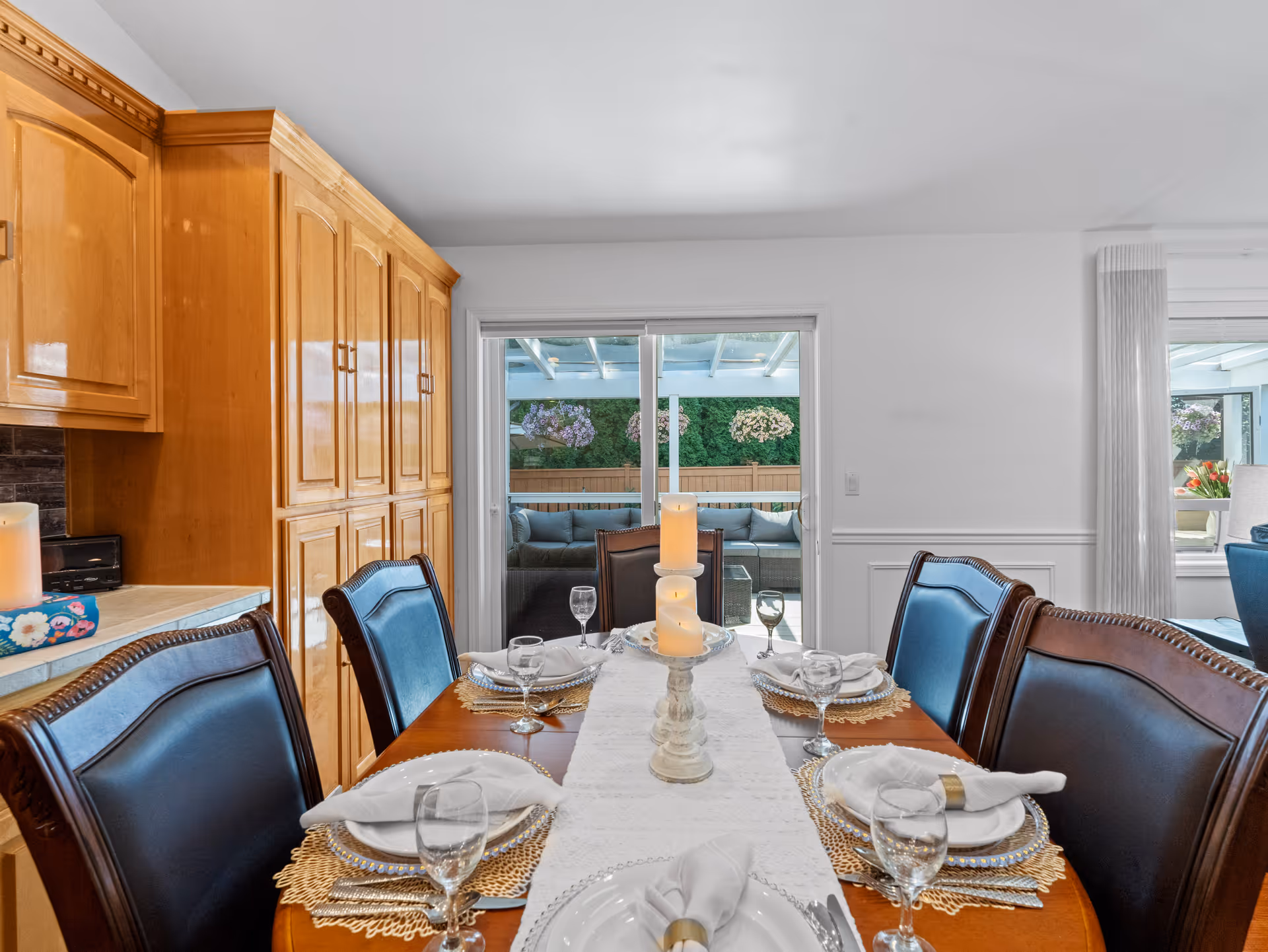 Dining room table set with candles, glassware, and plates in a bright interior.