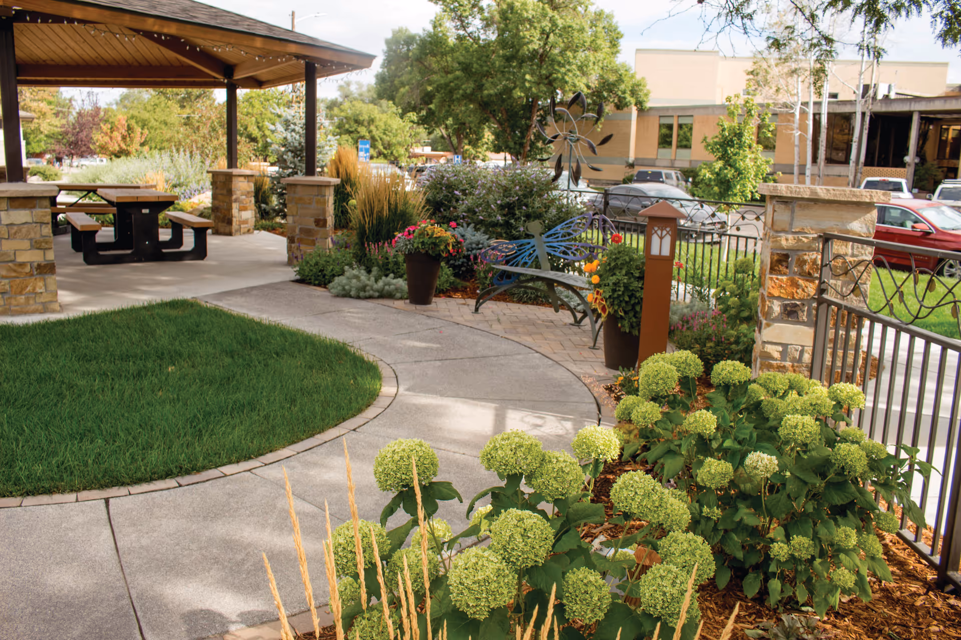 Well-kept outdoor courtyard with a pavilion, path, benches, and lush plants at HopeWest.