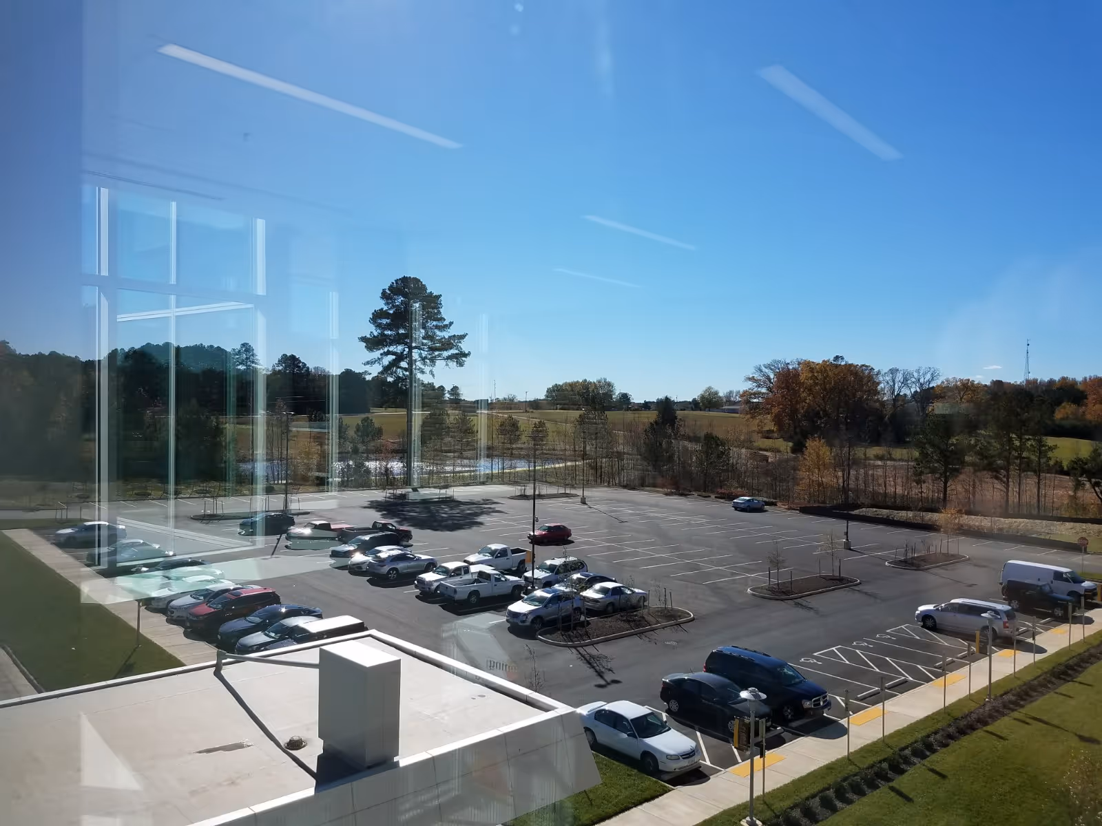 Parking lot with cars and trees visible through reflective glass exterior.