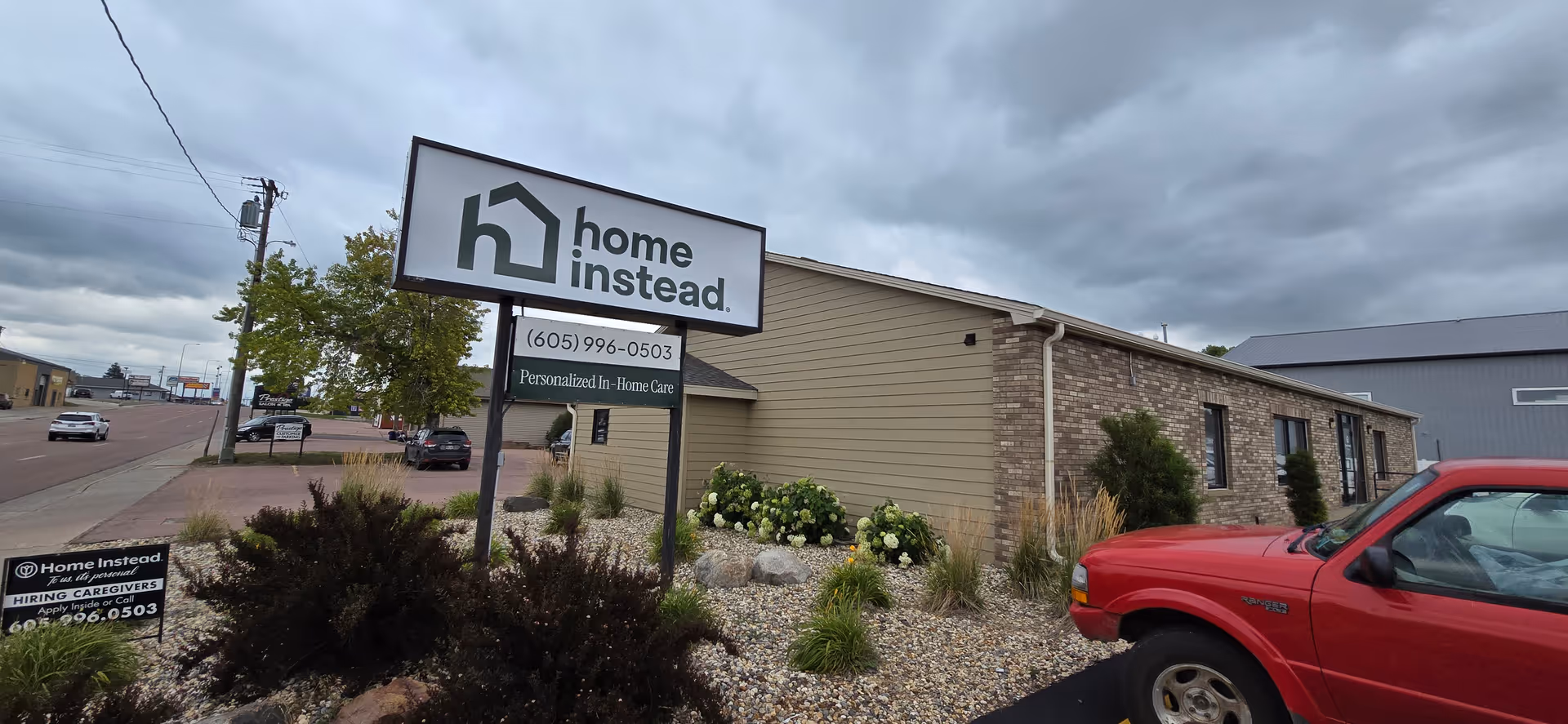 Exterior view of a Home Instead building with a large sign and landscaping.