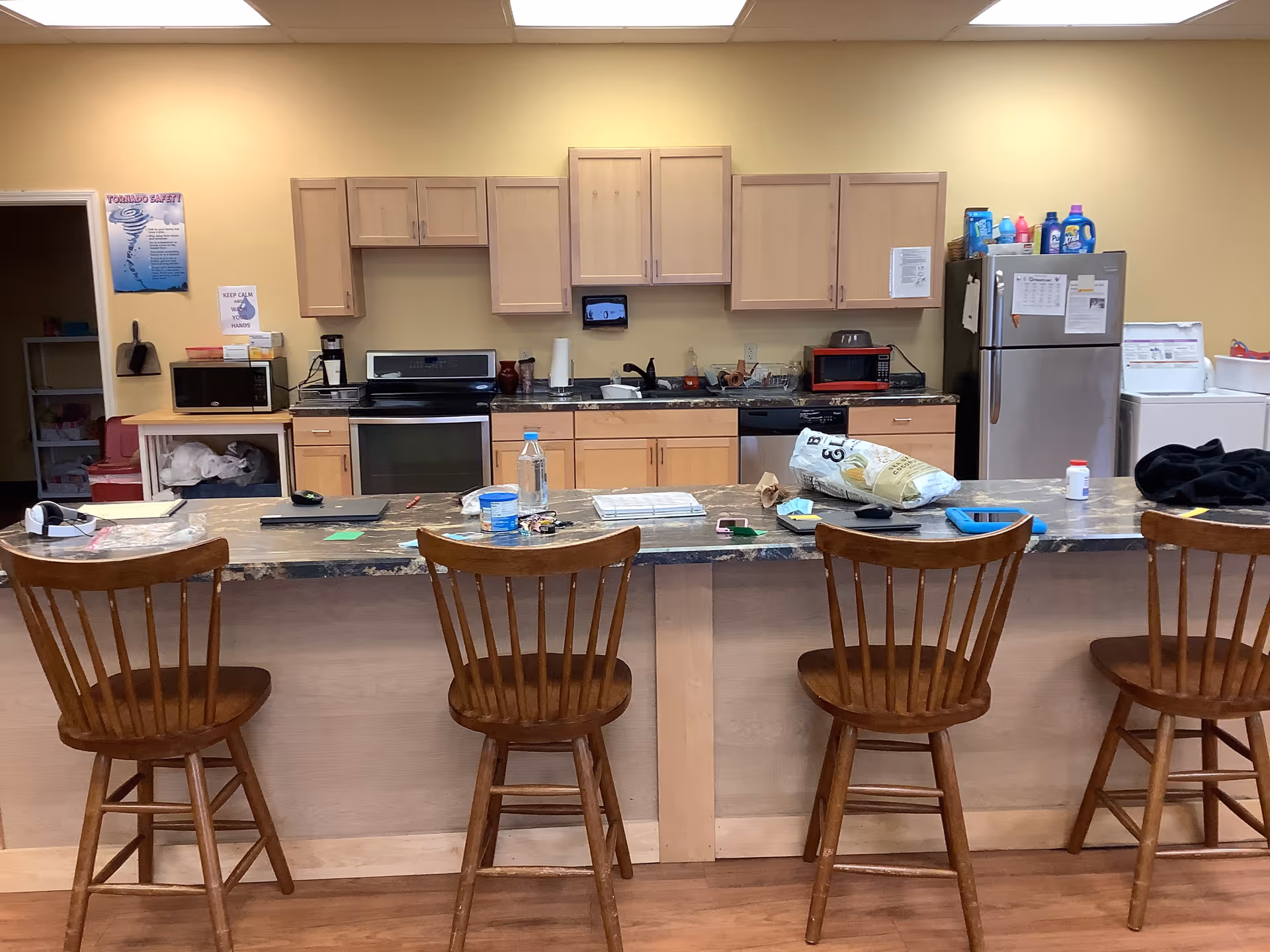 A kitchen with wooden cabinets and bar stools at a counter.