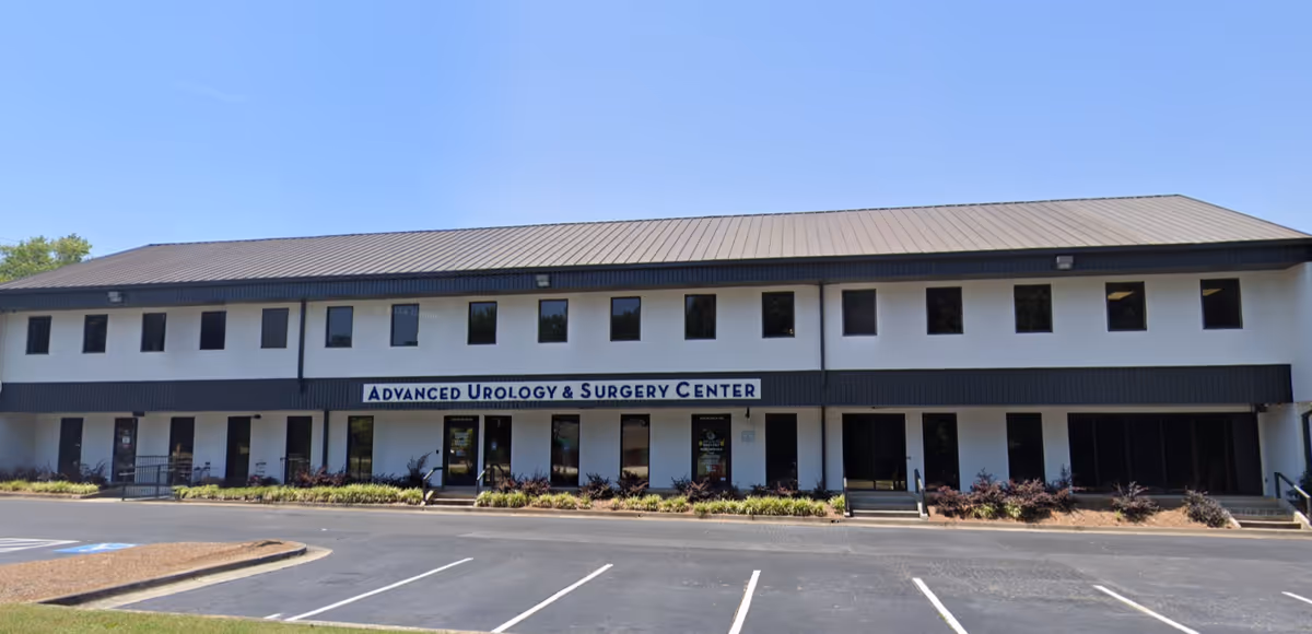 Two-story white medical building with dark trim and a sign reading Advanced Urology & Surgery Center