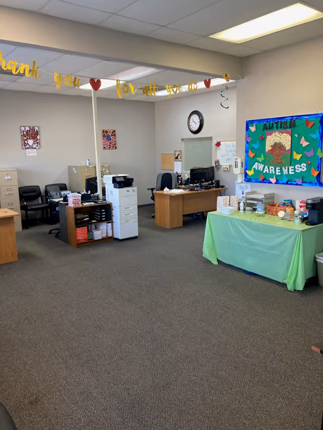Interior office area in NurseCore facility with desks, printer, and a green-draped table.