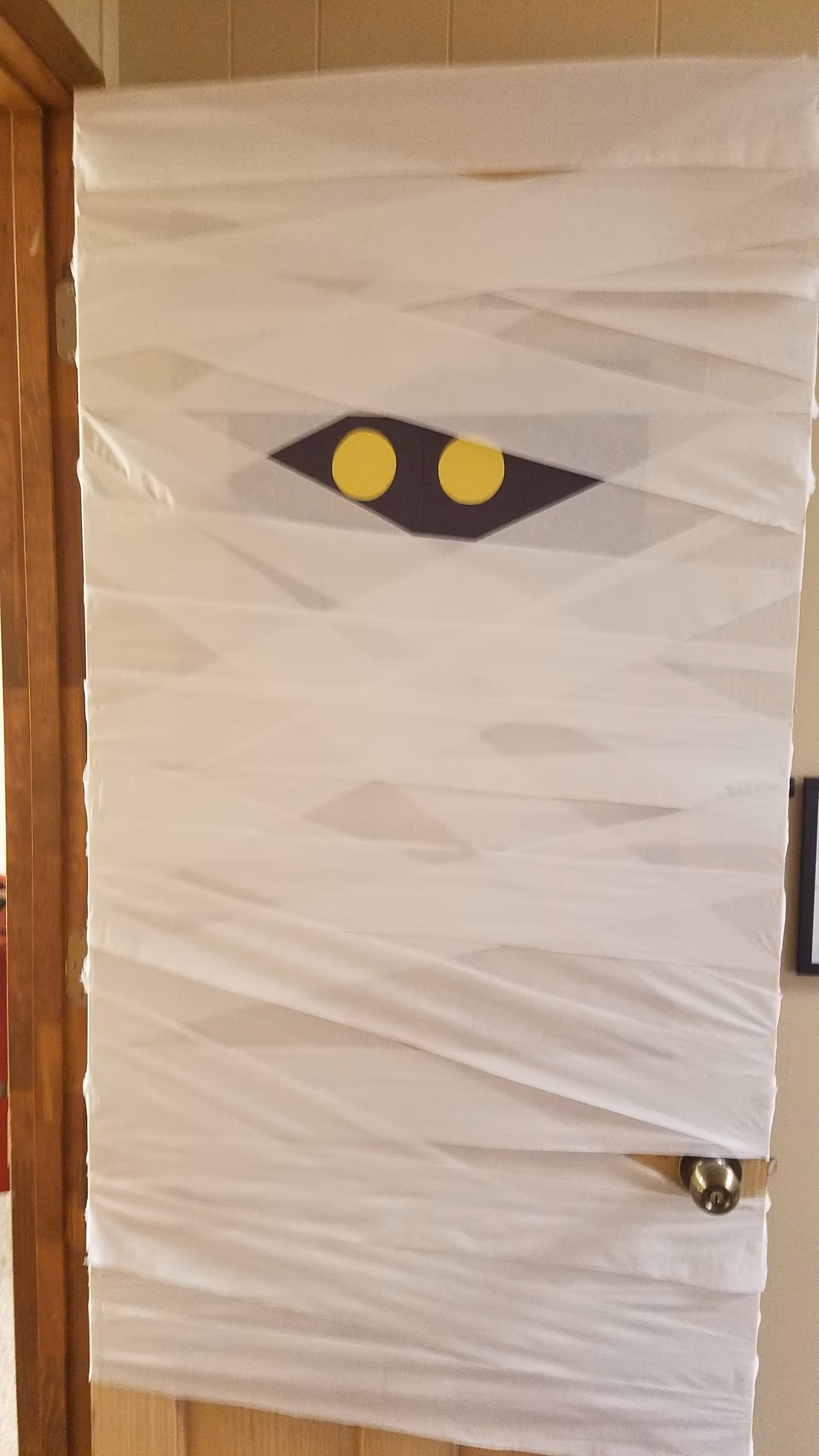 White door wrapped in plastic in a hallway with a black diamond and two yellow circles.