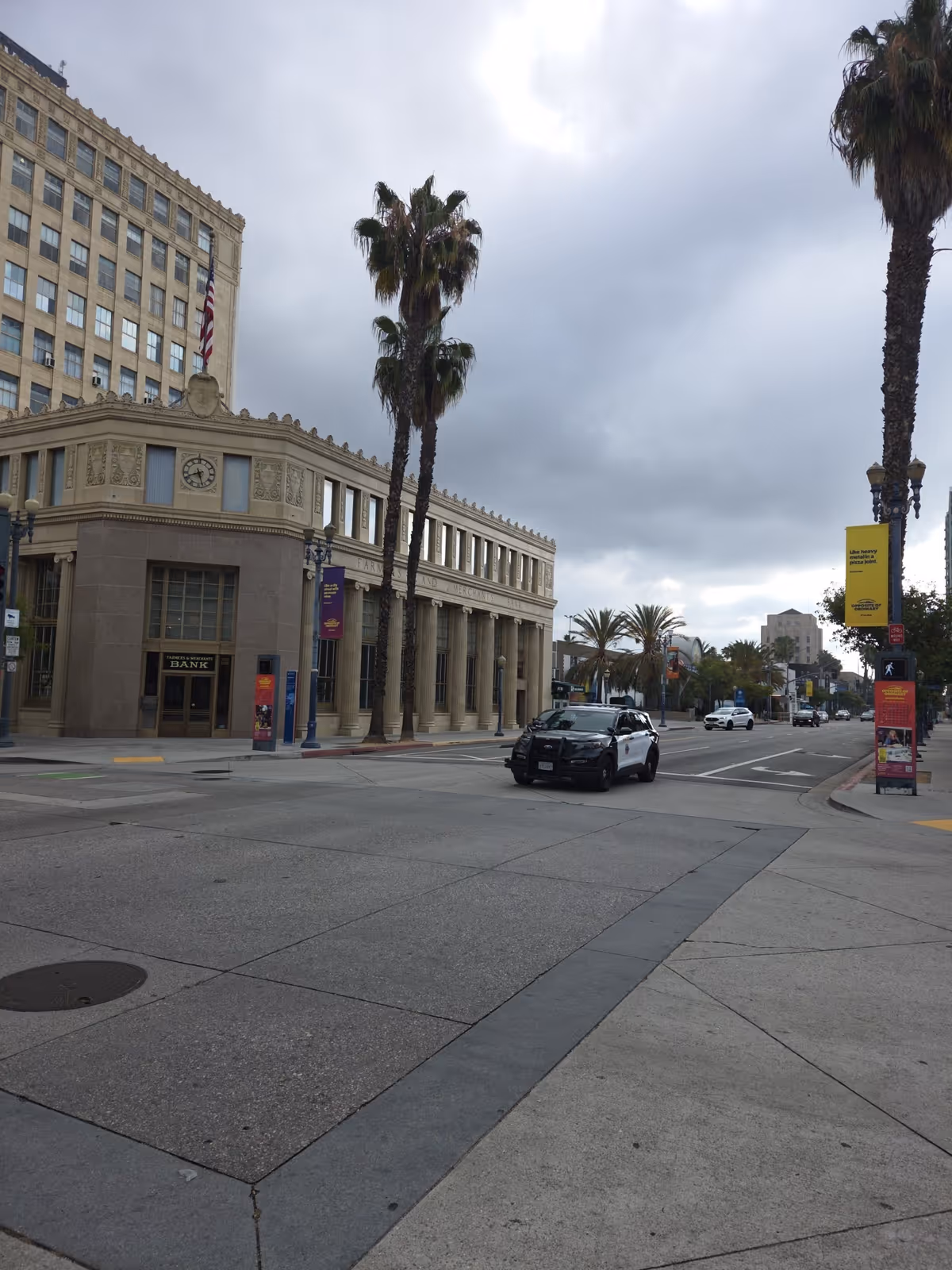 Urban street scene with a historic building front, tall palms, and a patrol car