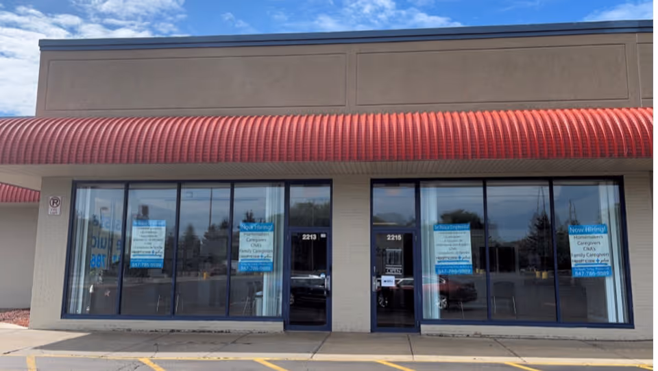 A storefront with large glass windows and blue hiring signs in a strip mall.