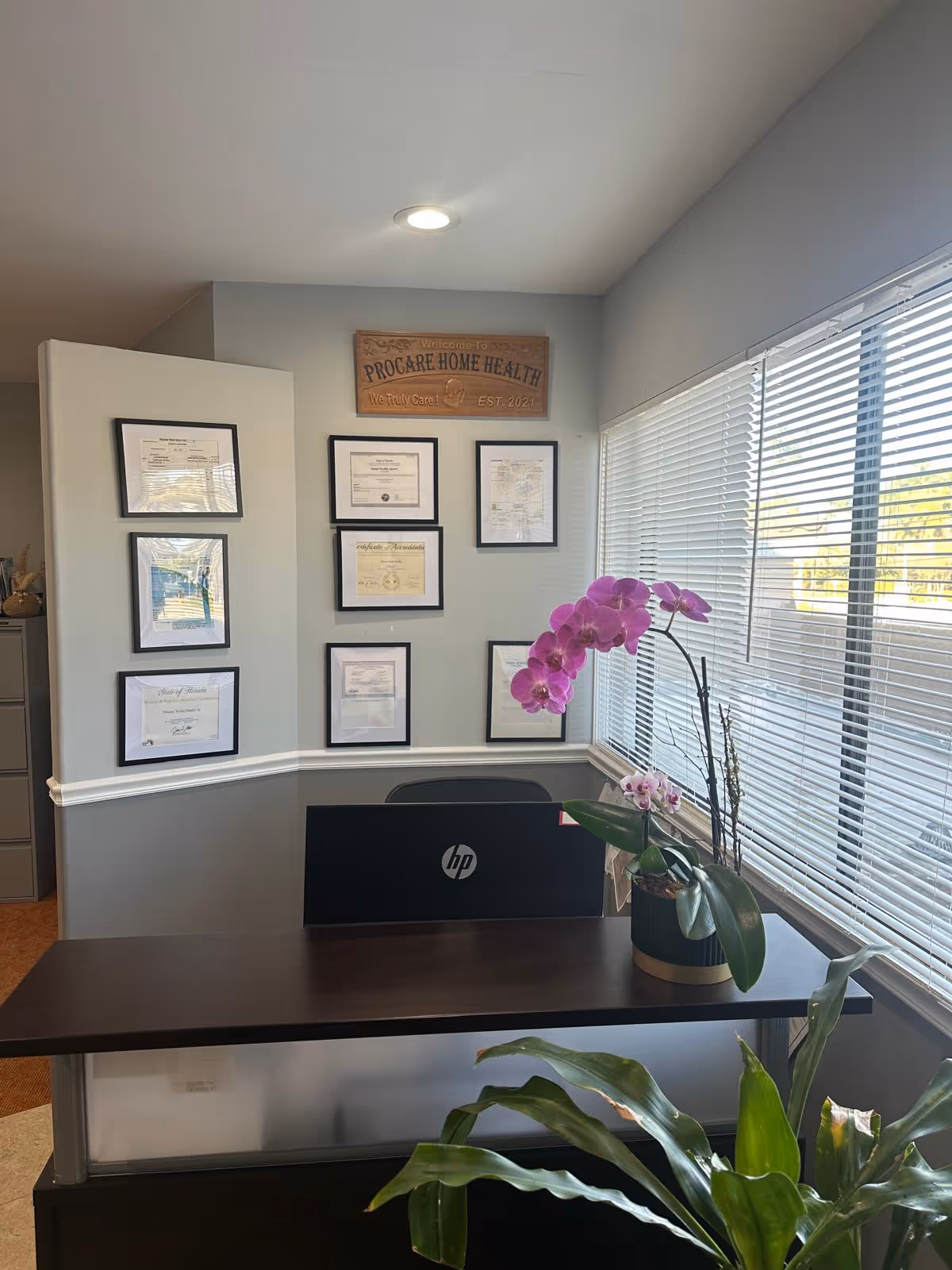 Reception desk in Procare Home Health with framed certificates and a purple orchid