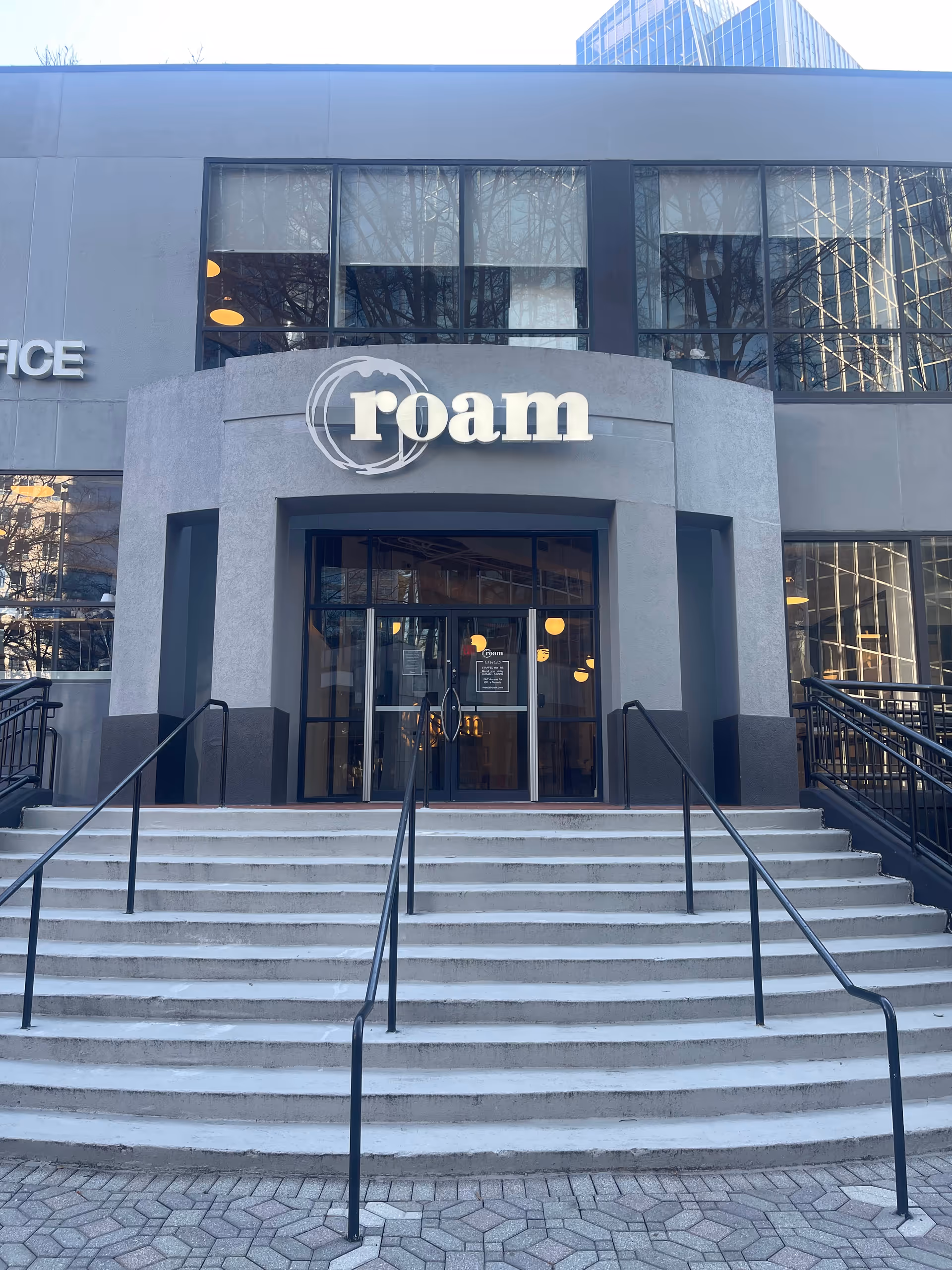 Modern building entrance with glass doors, large Foam sign, and concrete stairs.