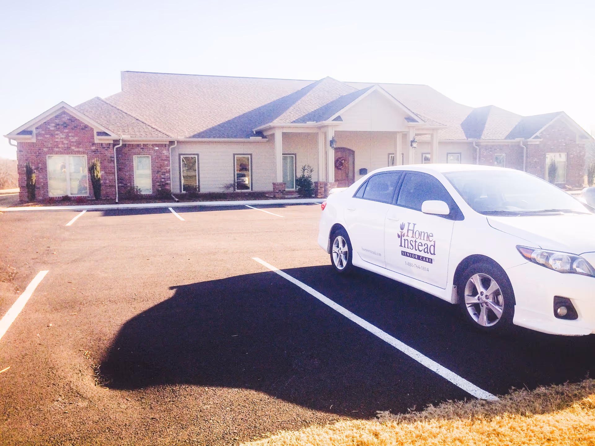 Single-story senior care building with a Home Instead van parked in front in a paved lot.