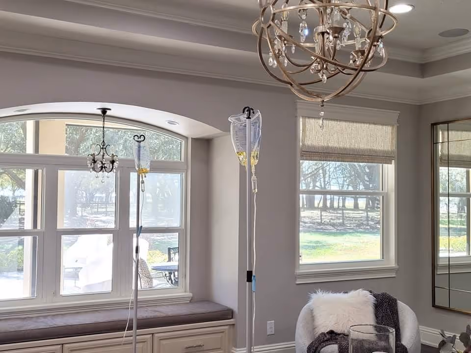 Bright living room with two IV stands near windows and a cushioned window seat.