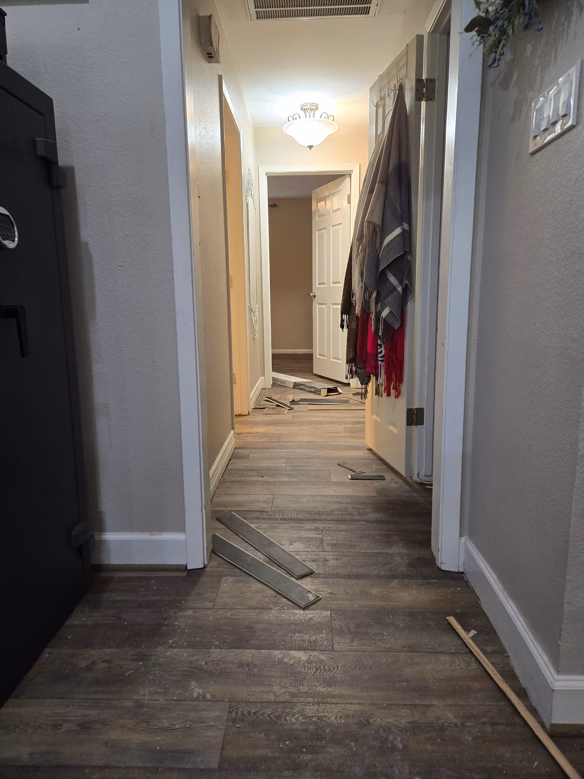 Narrow hallway in a senior living facility with coats hanging and debris on the floor