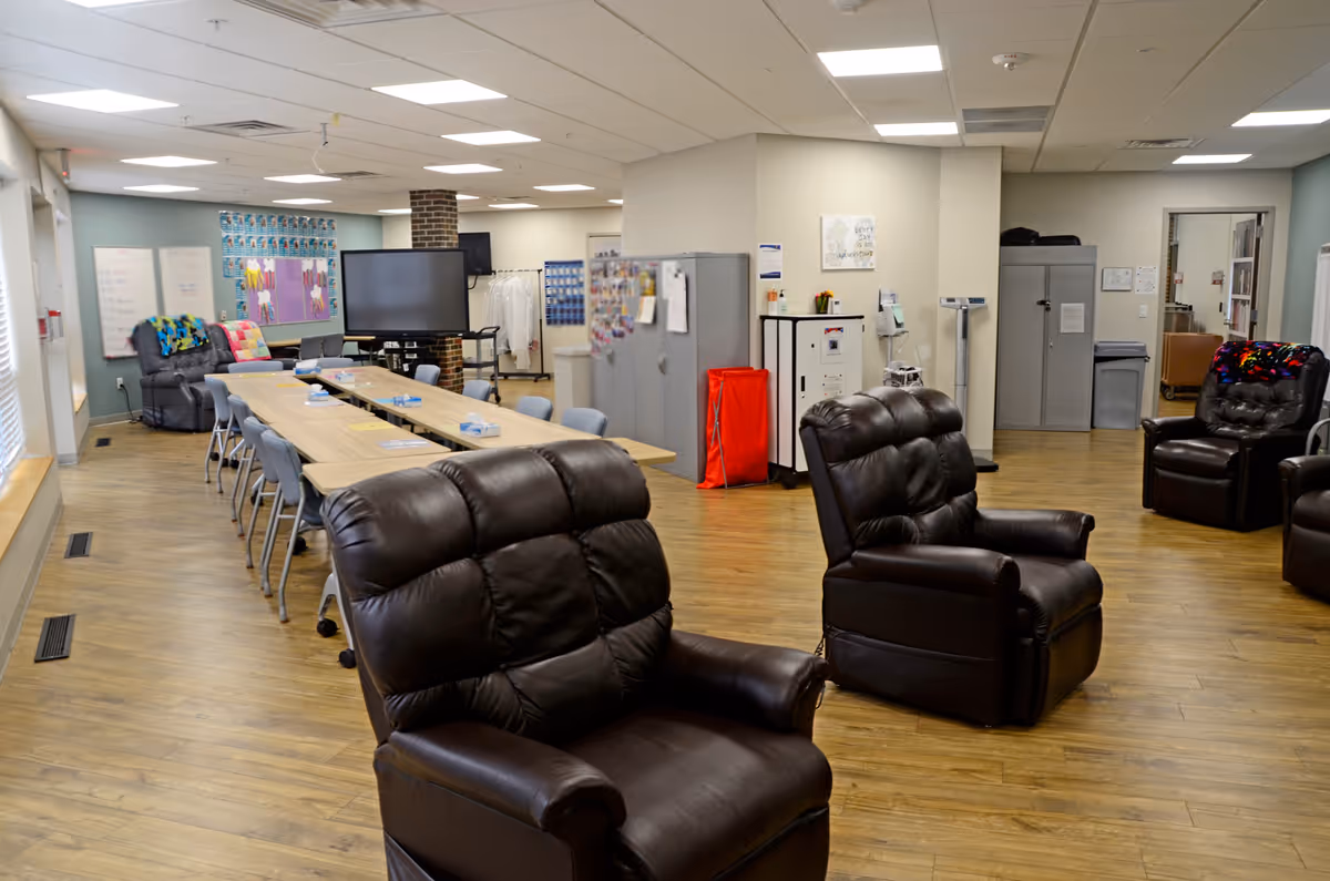 Interior common area of a senior facility with leather recliners and a long table.