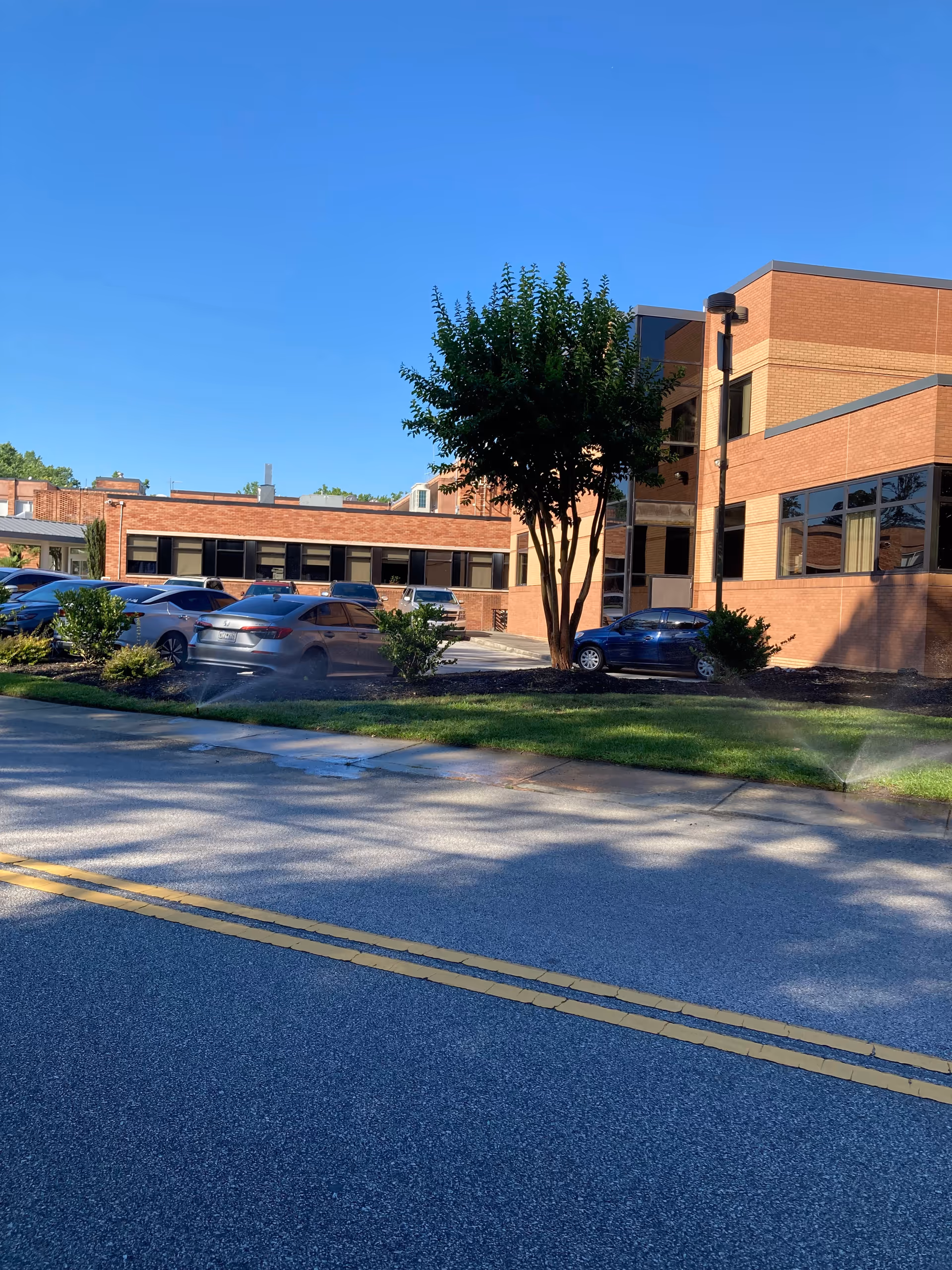 Exterior view of MUSC Health Kershaw Medical Center with brick building and parked cars.