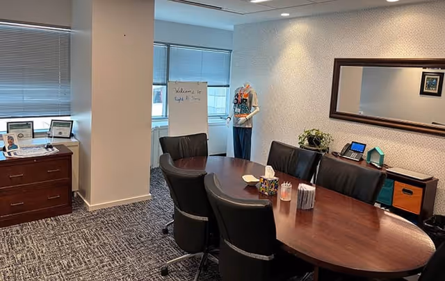 Office-style meeting room at Right at Home with round table and a person near a whiteboard.