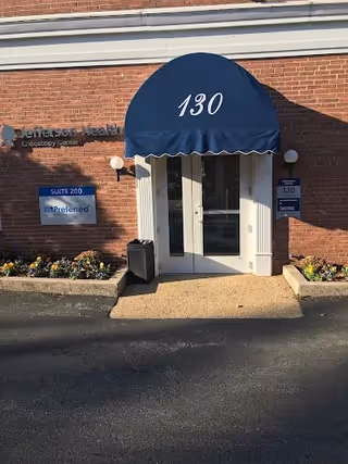 Front entrance of a brick building with a blue canopy labeled 130
