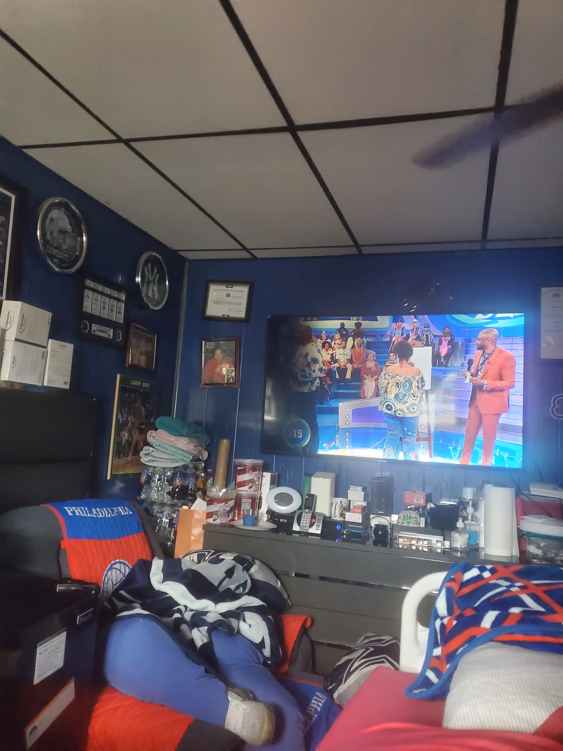 Cozy cluttered living room with a large TV and blankets scattered about.