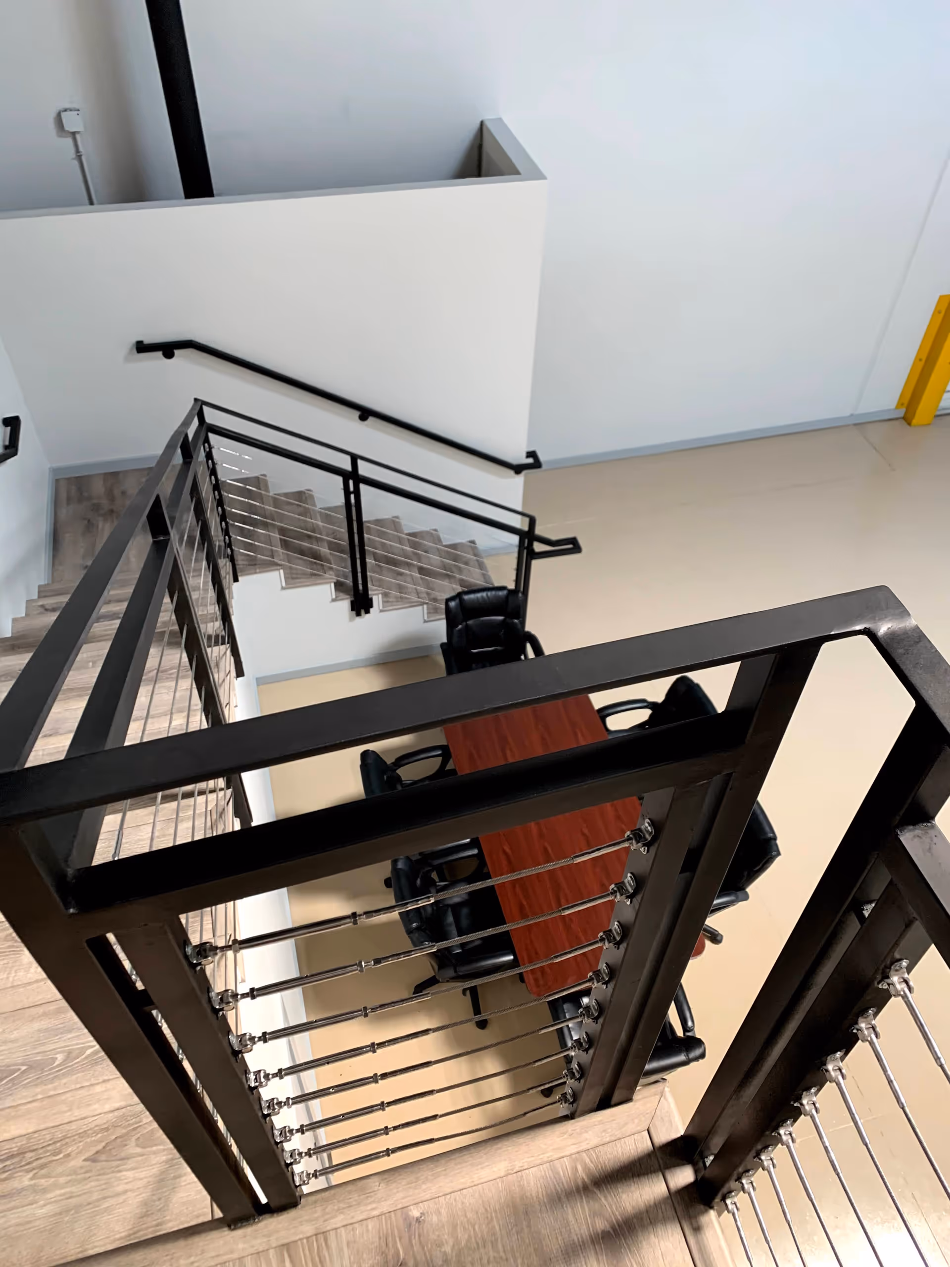 Interior stairwell with black metal railing; table and chairs visible on landing.