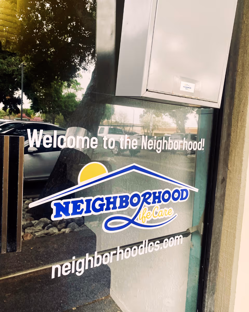 Glass entrance door with 'Welcome to the Neighborhood!' and Neighborhood Life Care logo visible outside.