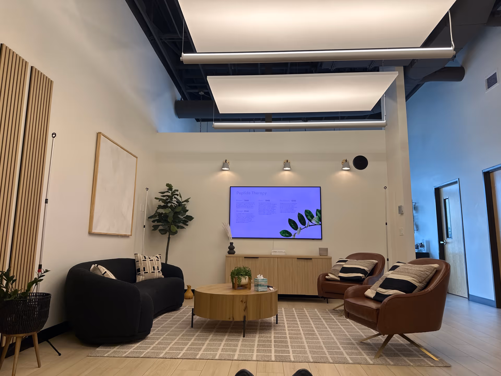 Modern, well-lit lounge area with sofas, chairs, coffee table, and wall-mounted TV.