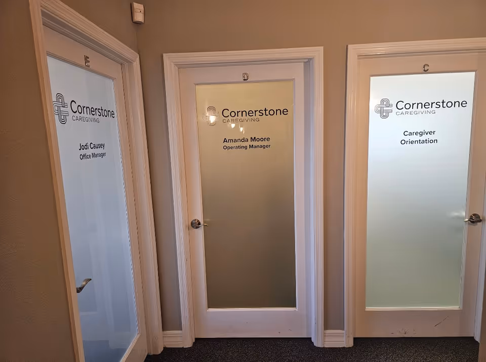 Three frosted glass doors line a hallway, each labeled with Cornerstone Caregiving roles and names.
