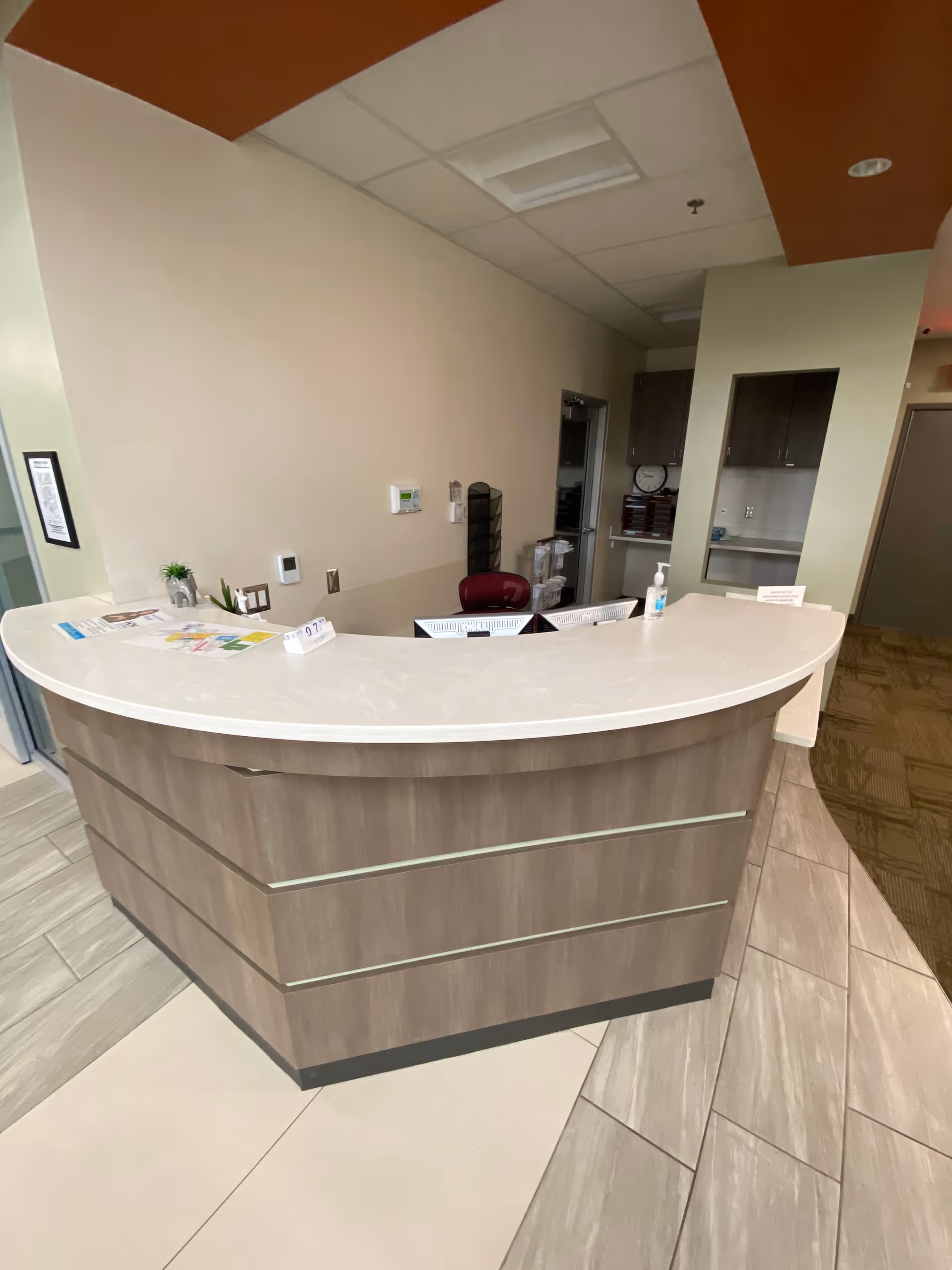 Curved reception desk in a neutral lobby with cabinets and doorway behind.