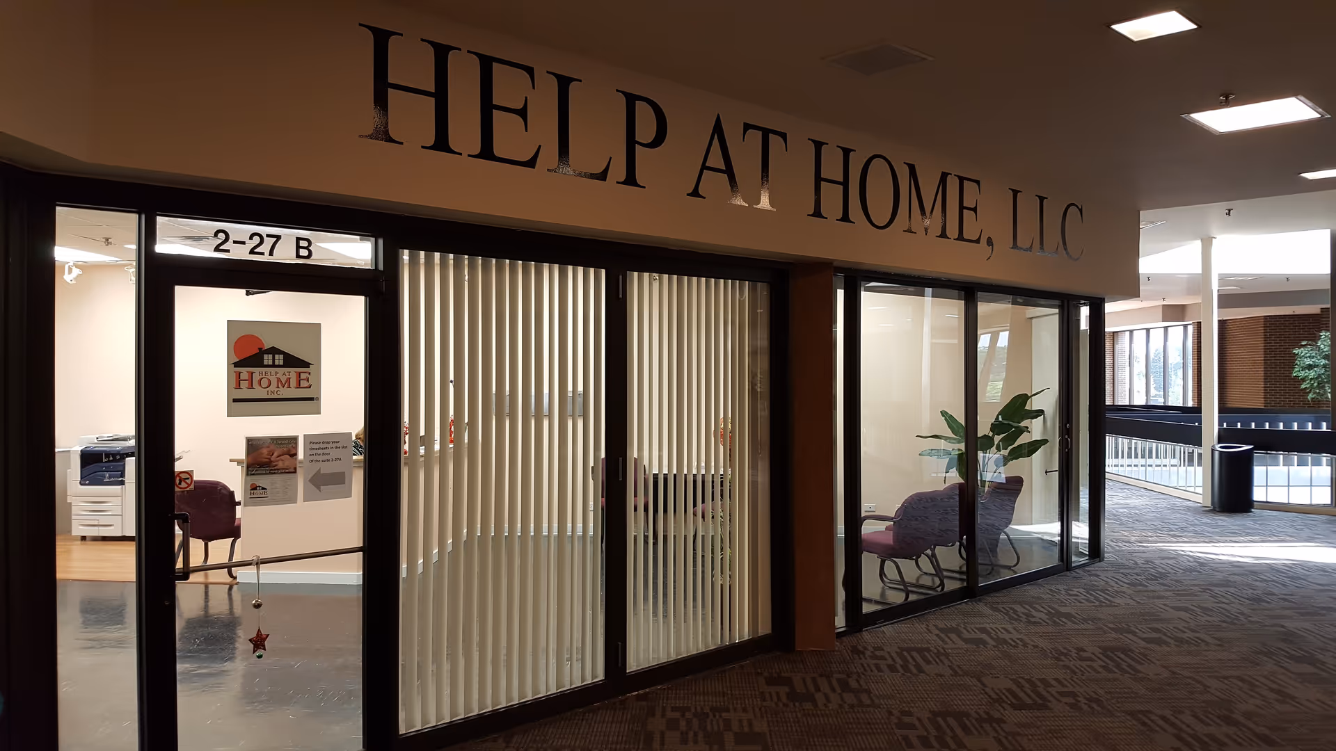 Interior lobby with glass doors labeled Help at Home, LLC and visible office seating.