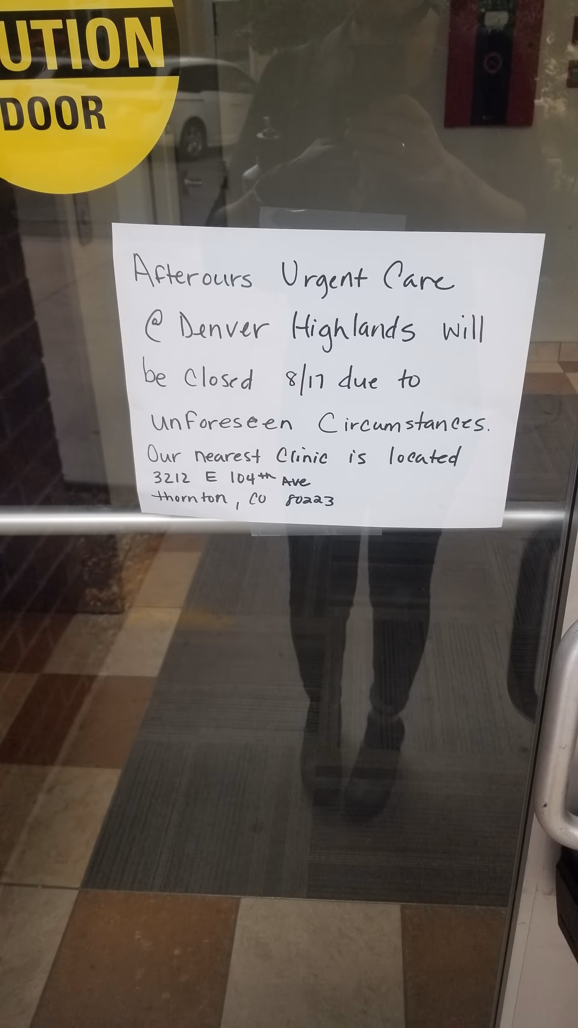 Handwritten closure notice on glass door at AfterOurs Denver Highlands Urgent Care Clinic.