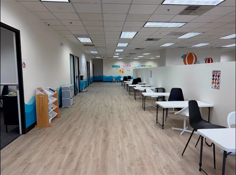 Long brightly lit hallway with tables and chairs arranged for activities.