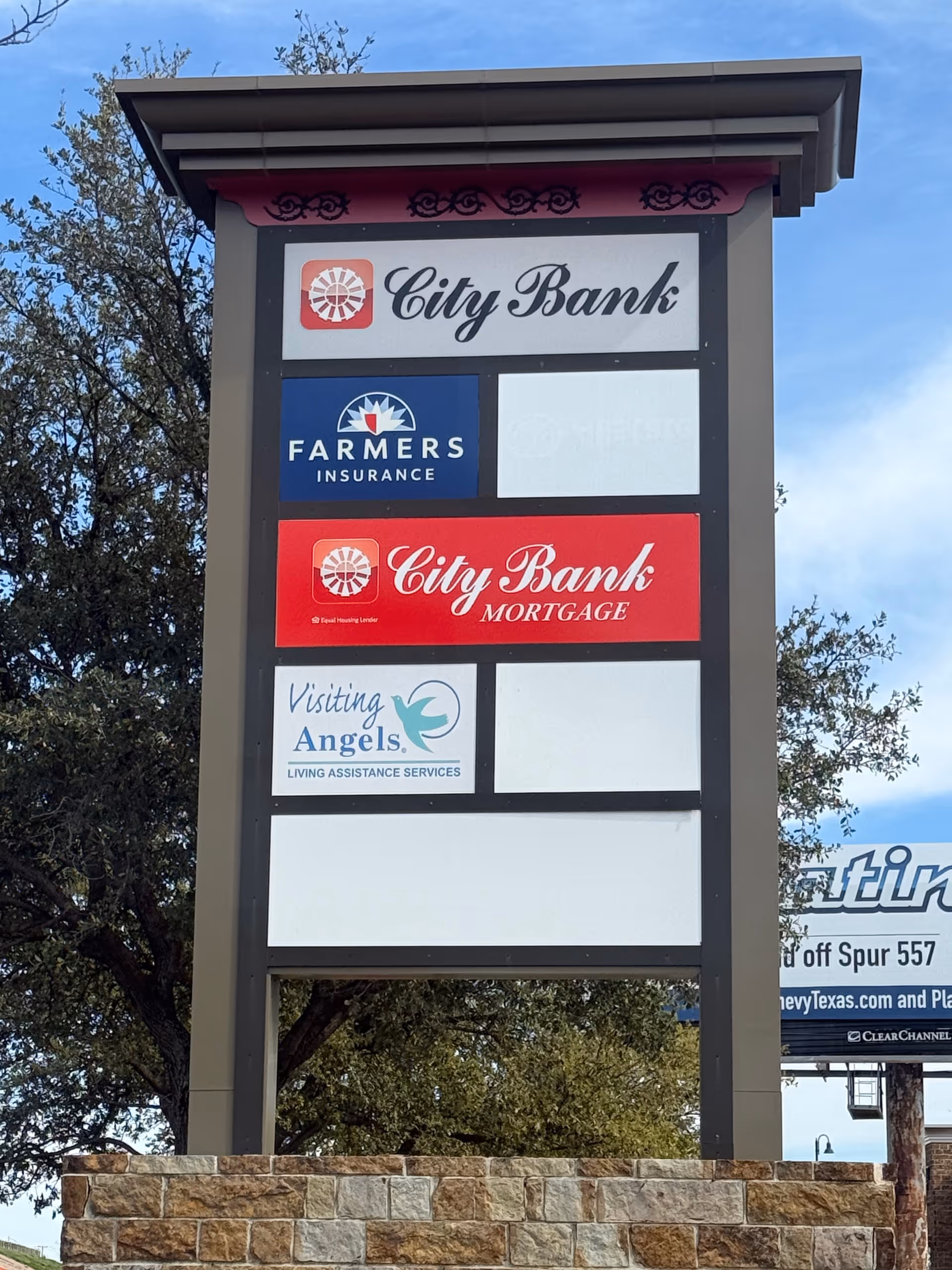 Tall outdoor signboard displaying Visiting Angels and other business logos in Waxahachie.