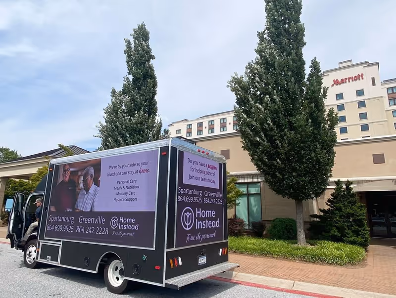 A Home Instead service truck parked outside the entrance of a building.