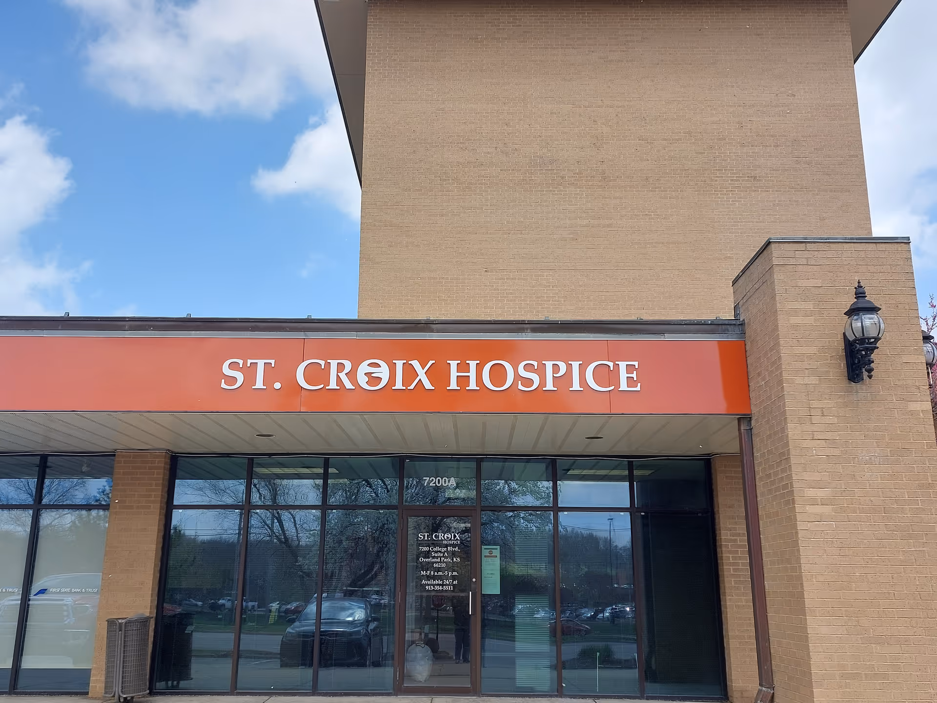 Exterior view of St. Croix Hospice building with an orange sign and glass entrance doors.