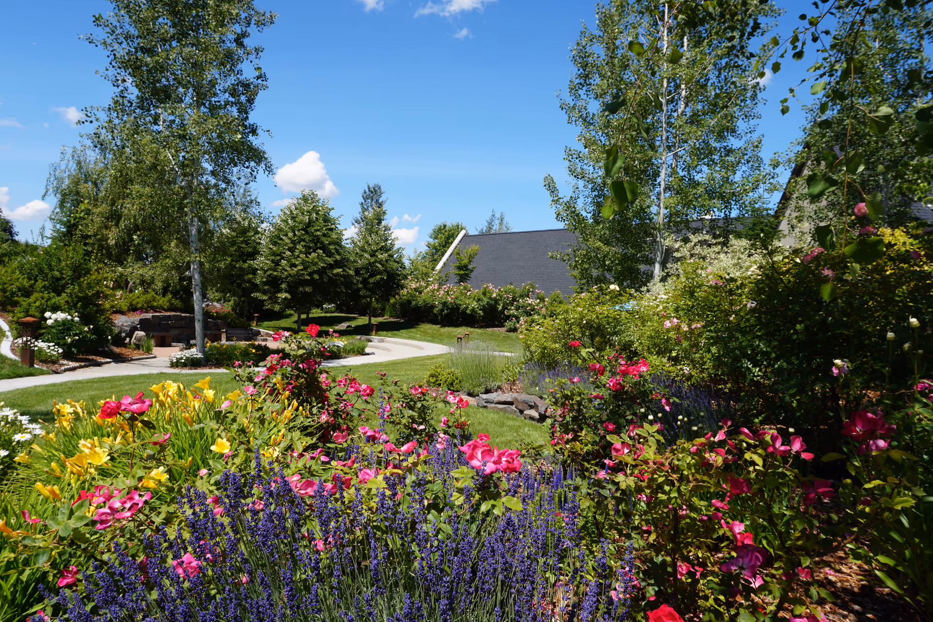 Colorful flower beds and a winding path in a sunny outdoor courtyard.